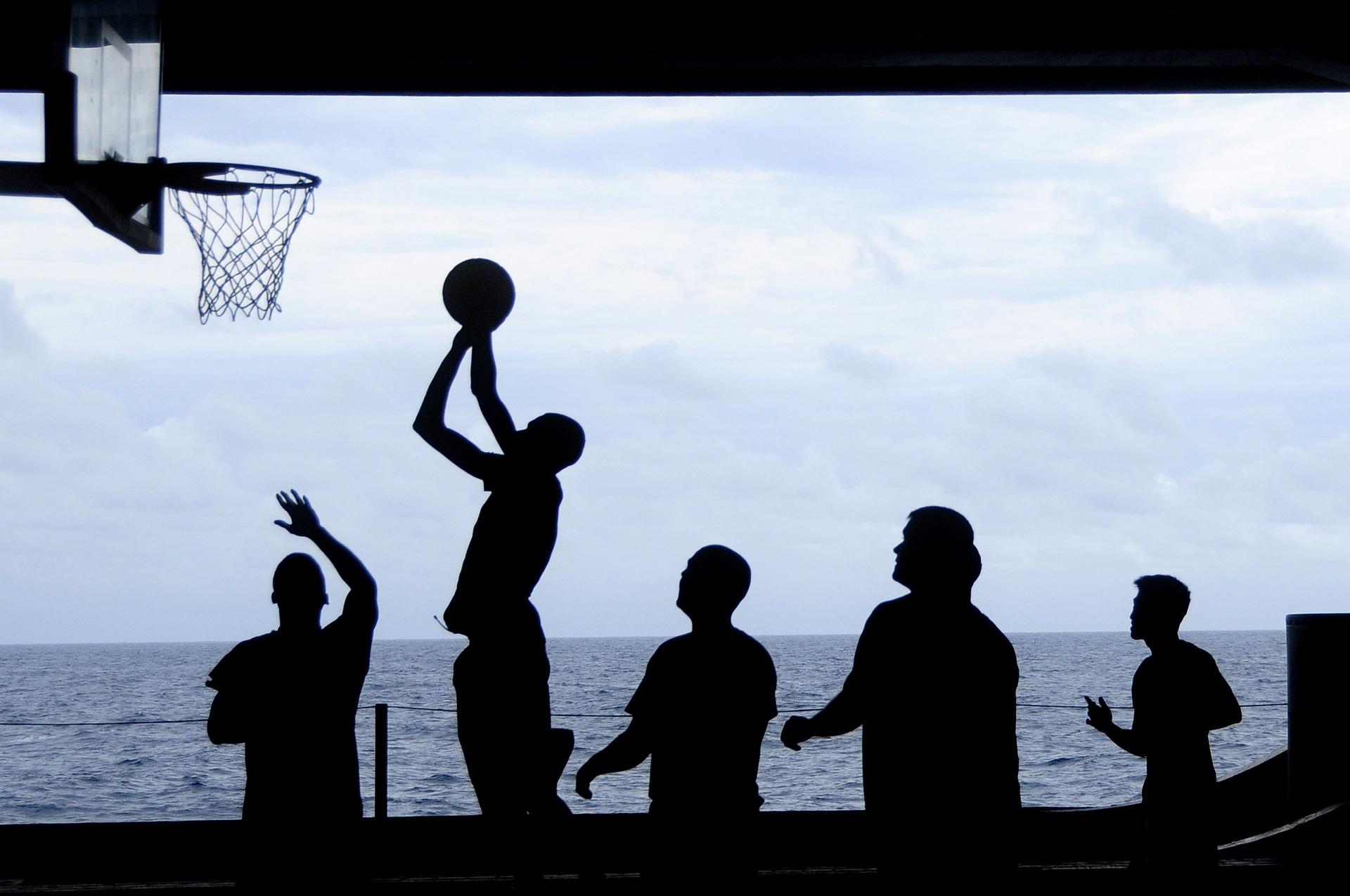 Silhouettes of multiple people playing basketball.