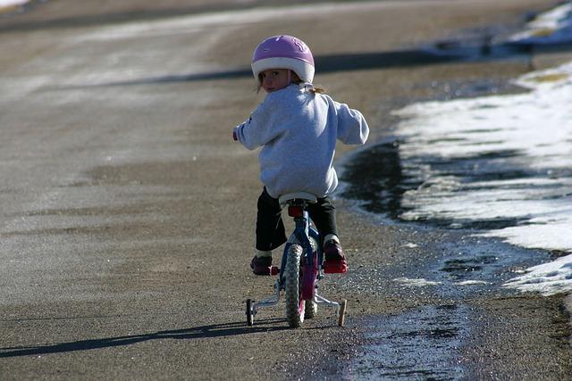 A little girl riding her bike by the beach and looking back.