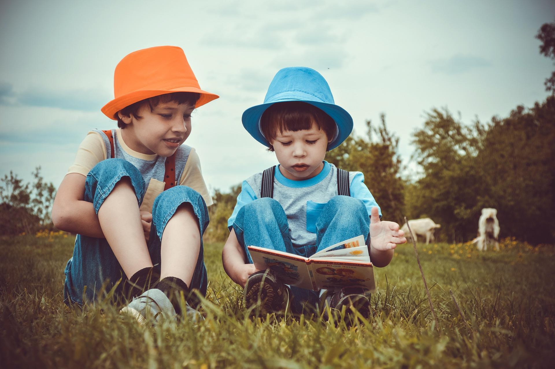 Two kids reading a story in a field.