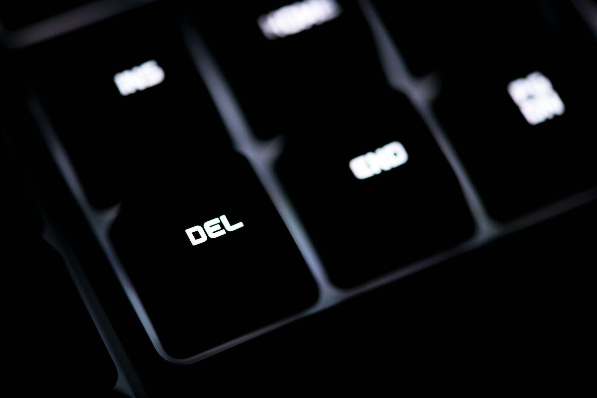 Closeup of a black keyboard with the DEL key highlighted.