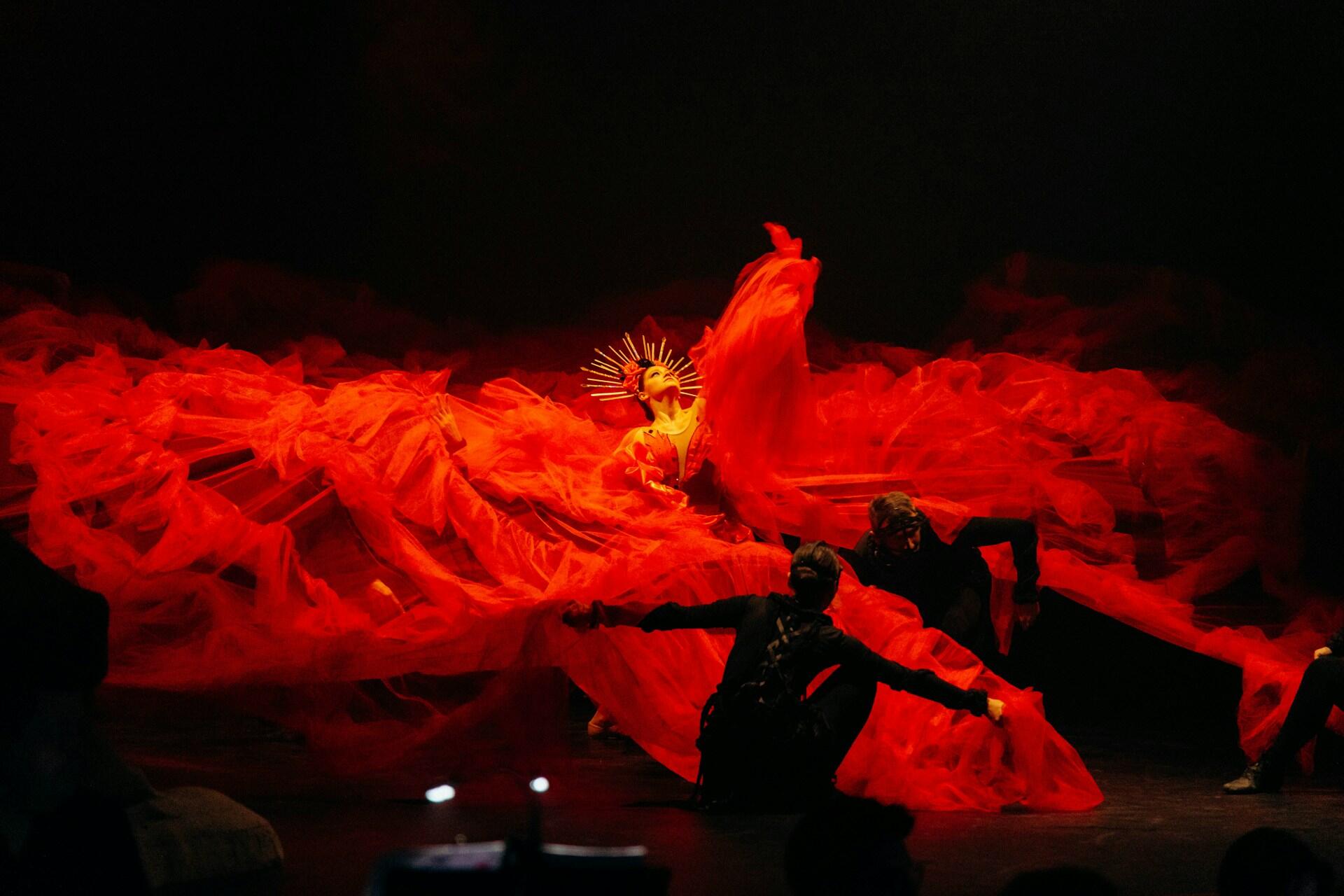 Flamenco dancers performing on stage with flowing red costumes