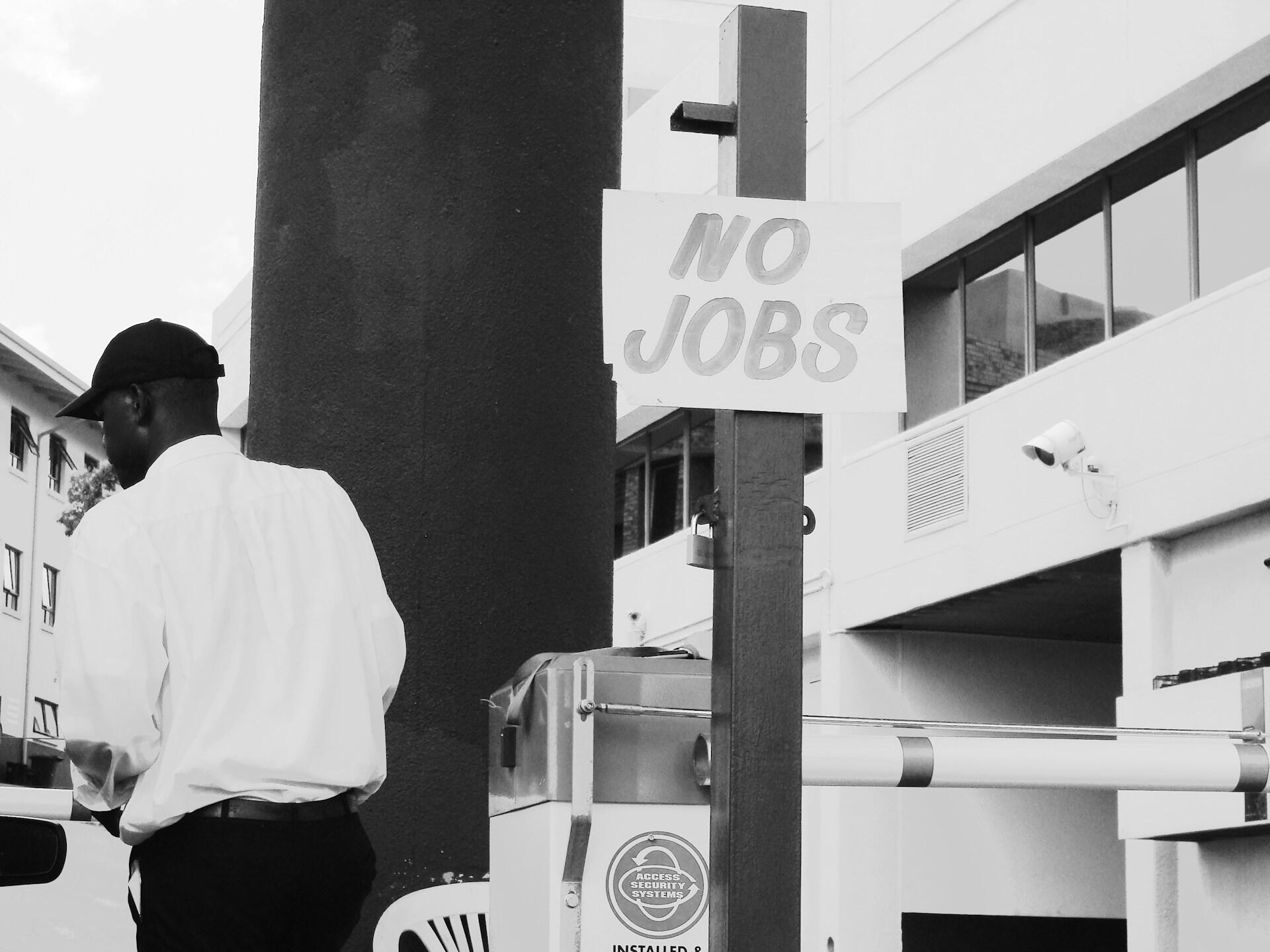 A man walks past a 'no jobs' sign.