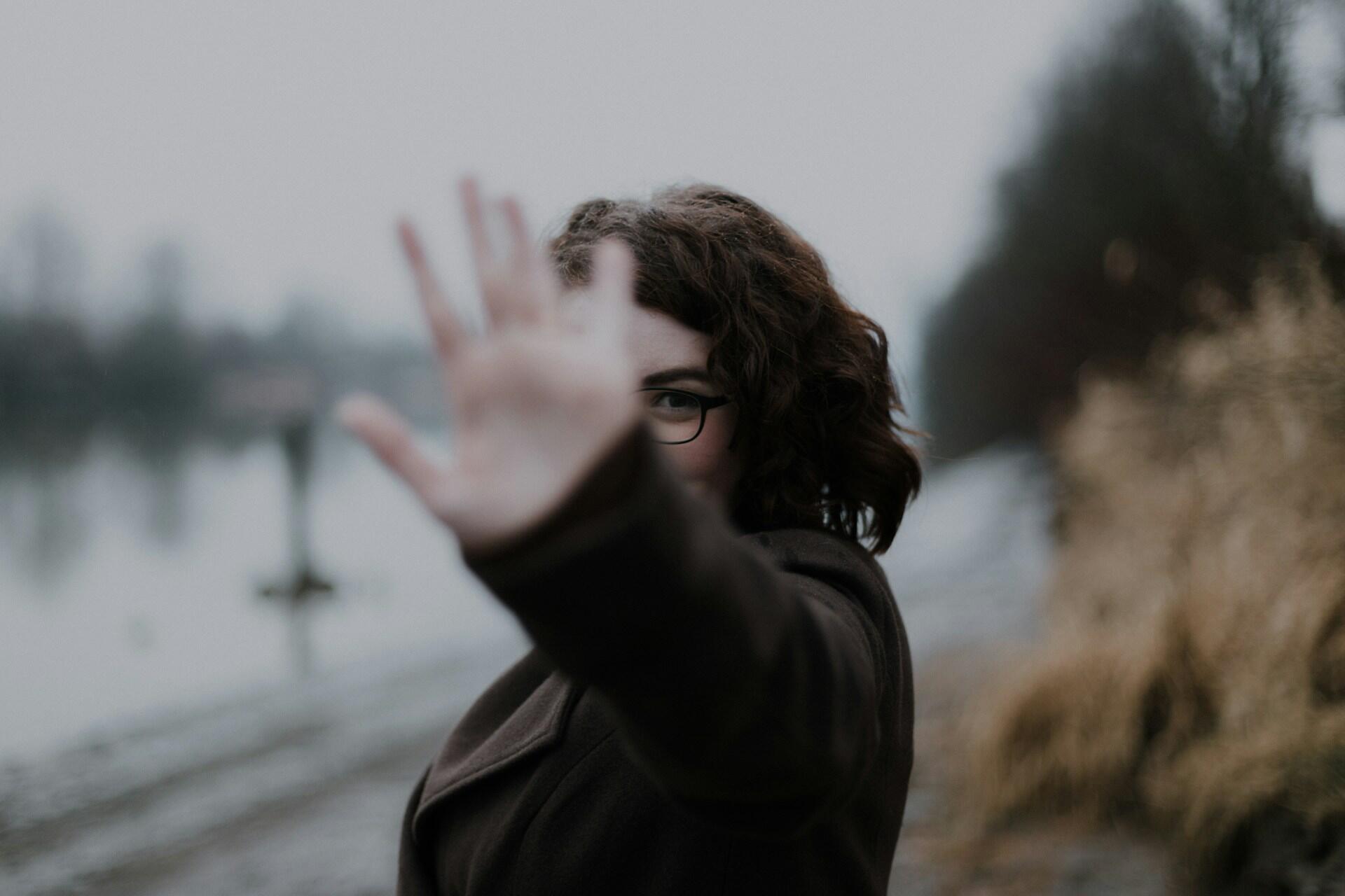 A woman holding her hand up in the halt gestrure.