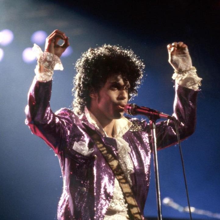 Prince raising his hands on stage.
