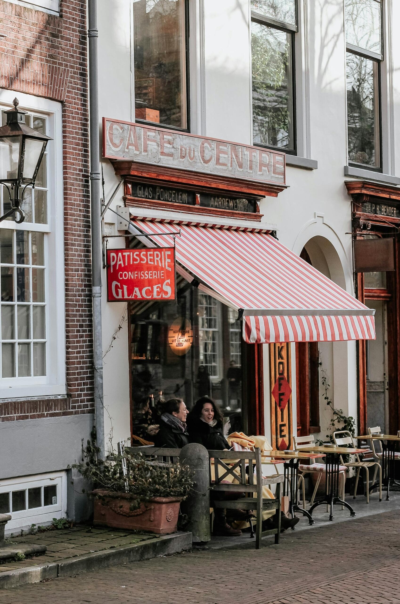 Two people sitting outdoors at a cafe table. 