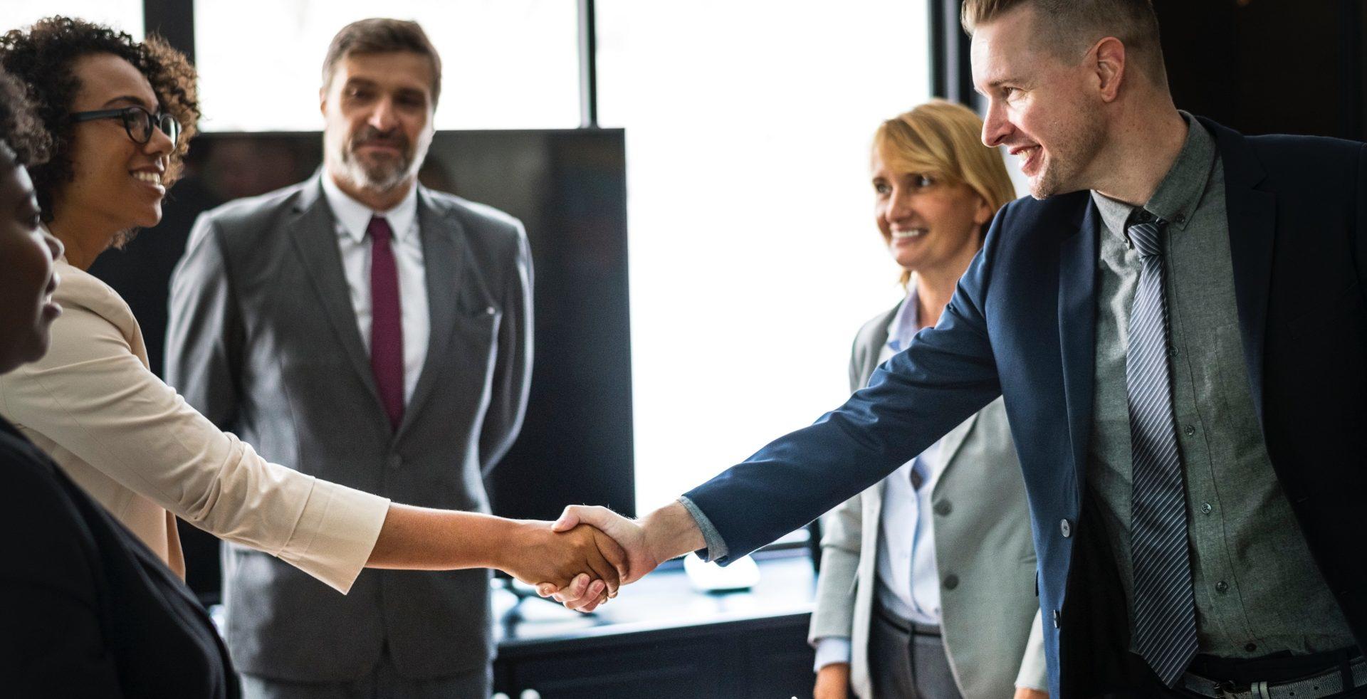 A small group of people dressed in office clothes stand and introduce themselves to each other.