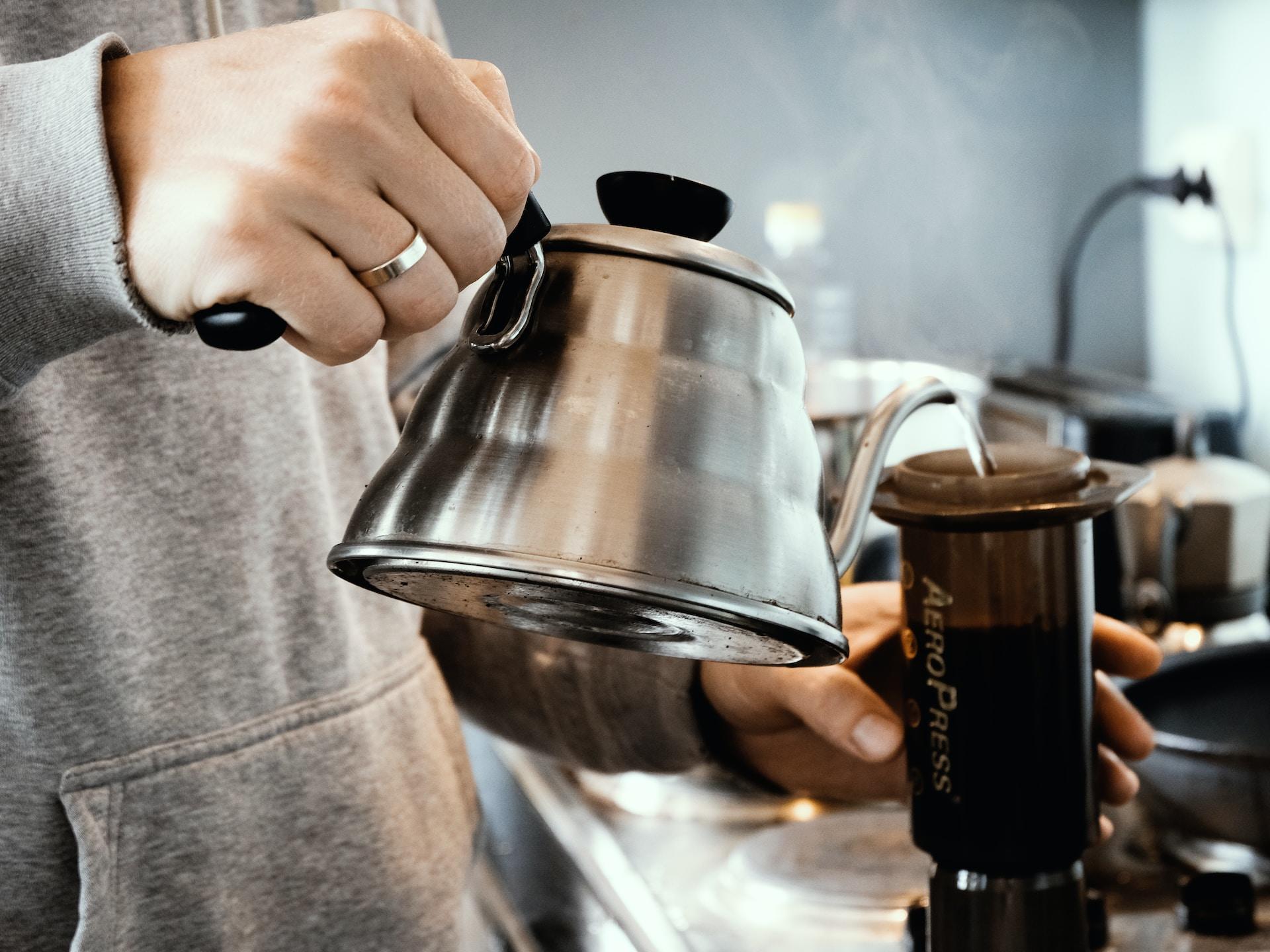 Man pouring water from a kettle into a coffee press.