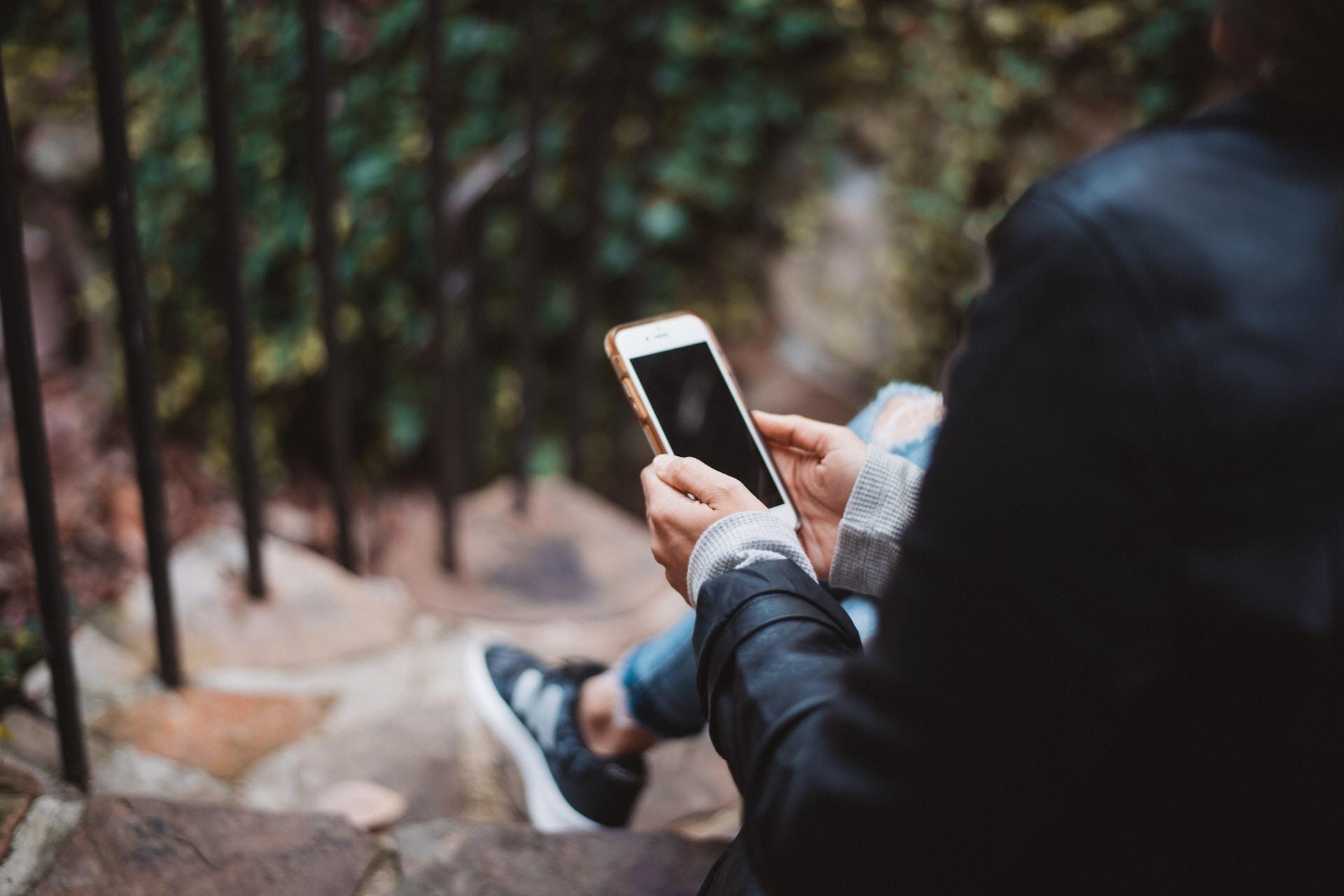 Woman sitting on a staircase with a mobile phone in her hand.