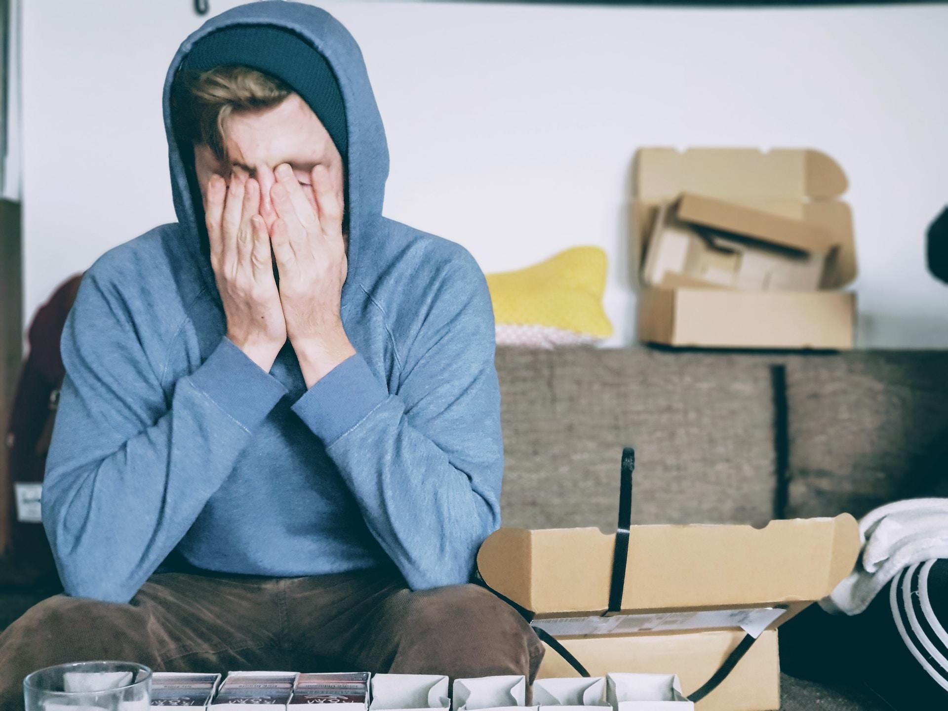 Guy sitting with his face in his hands.