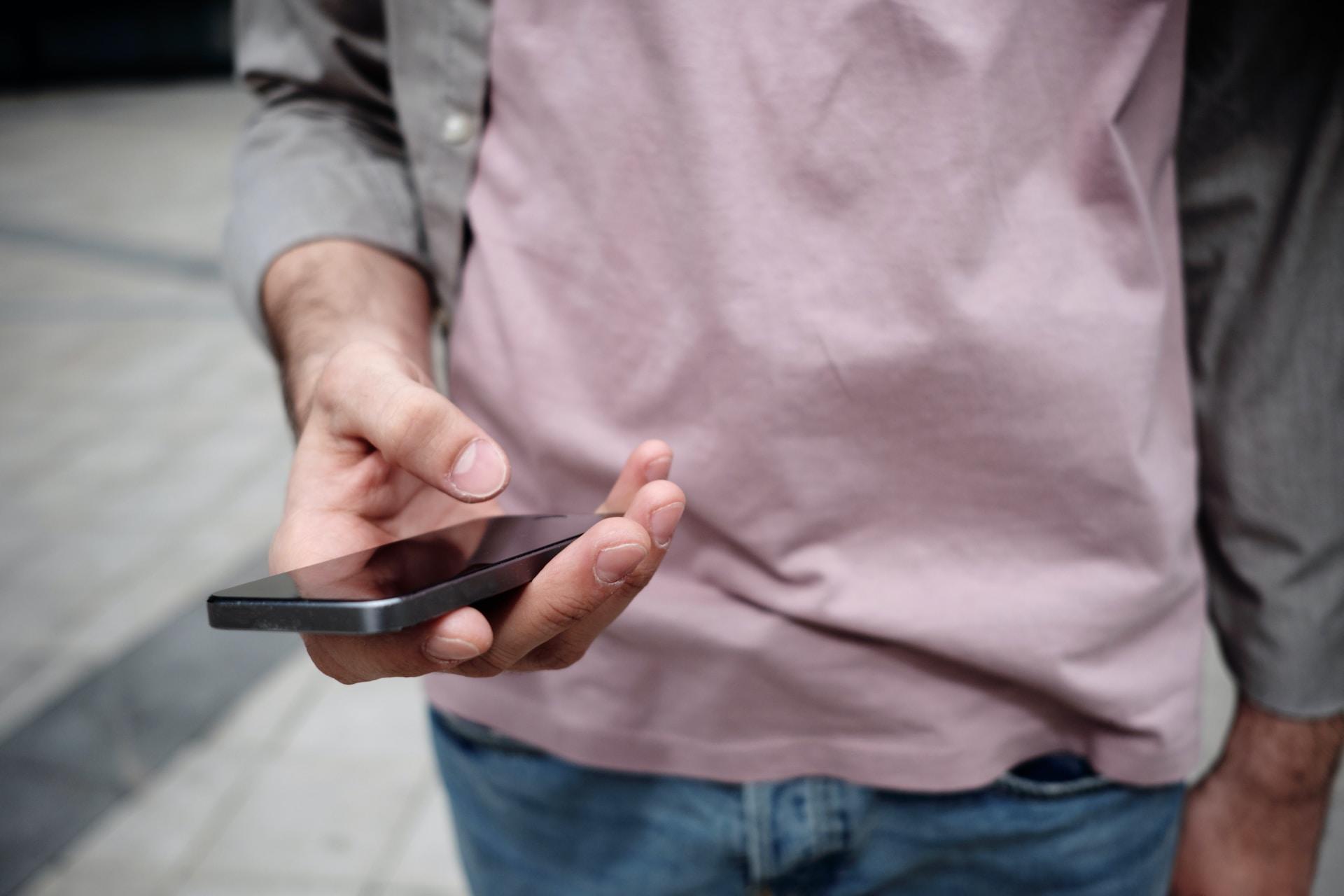 Person standing up holding a mobile phone.