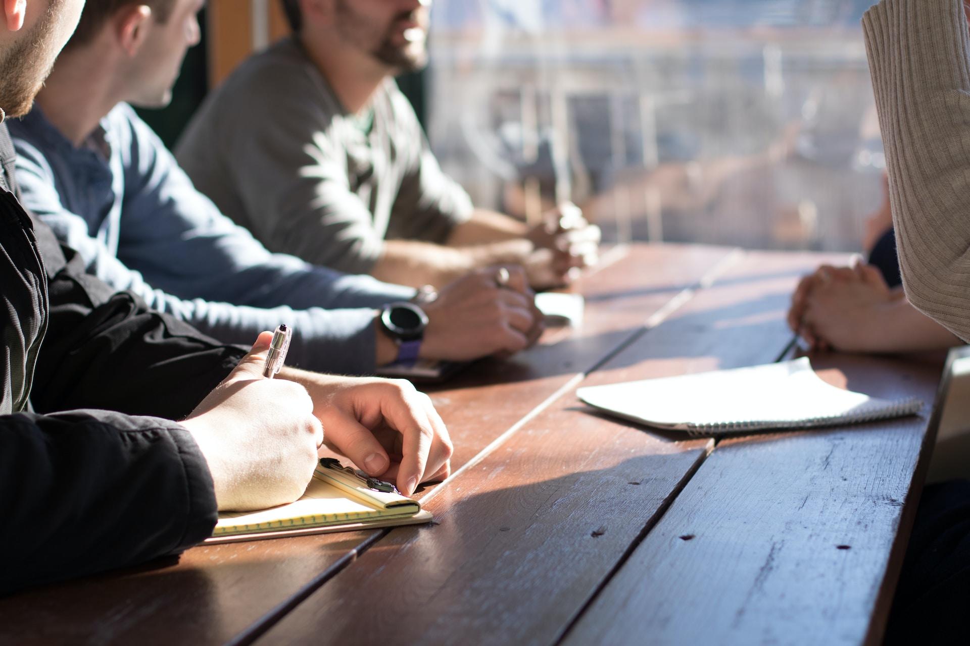 A group of four people sitting with notebooks in front of them.