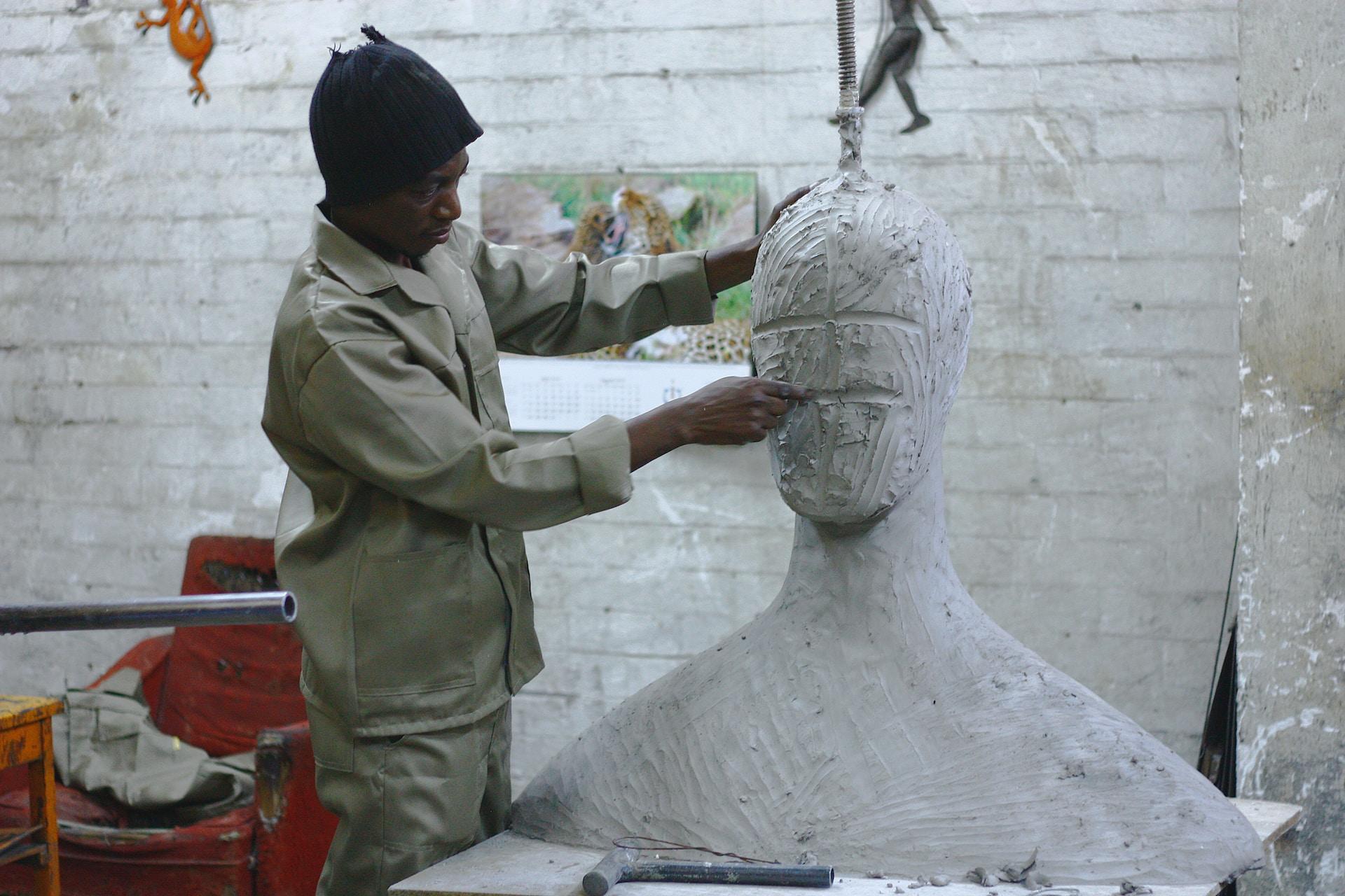 Artist sculpting a large bust.