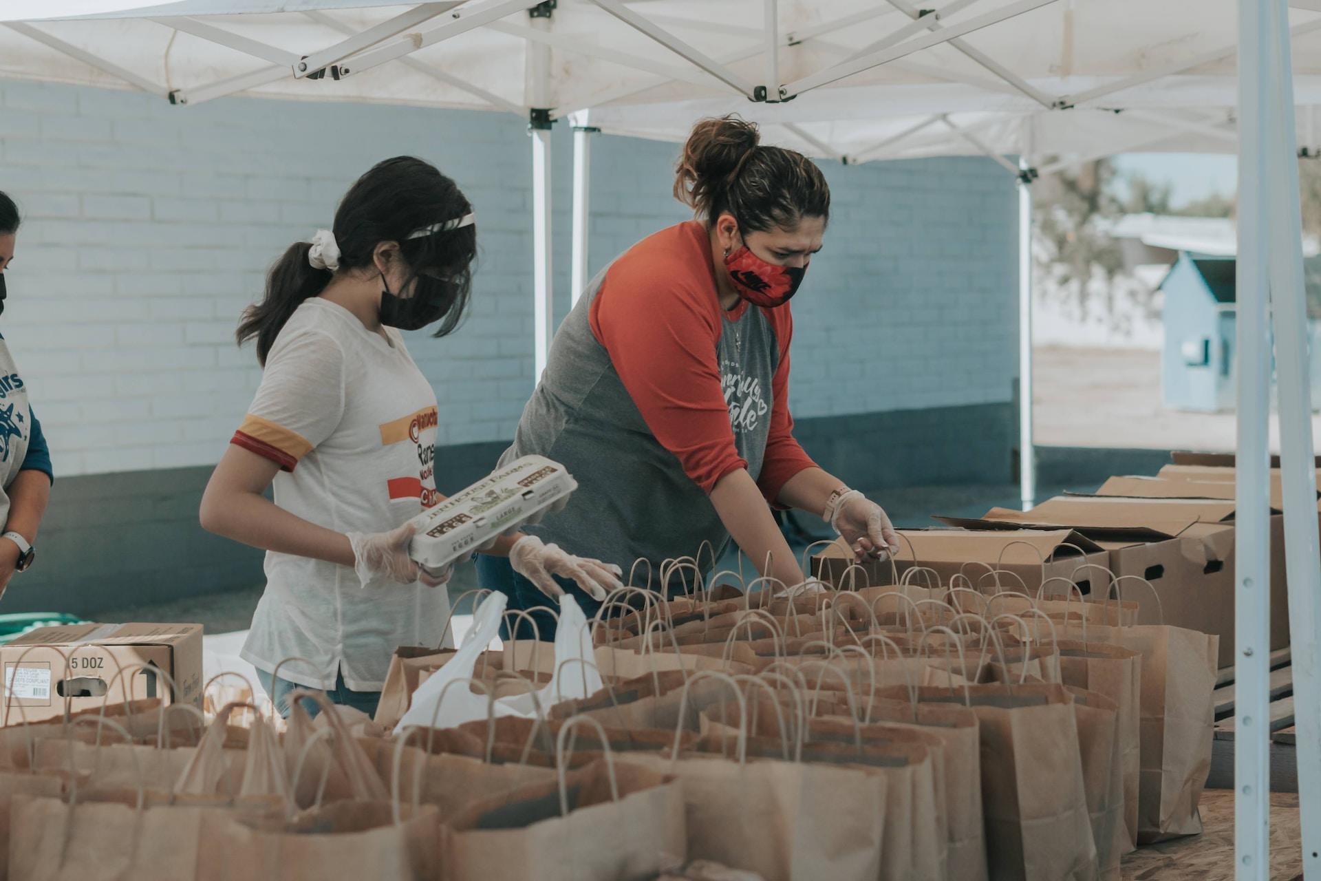 A girl and a woman volunteer to sort food into different bags.