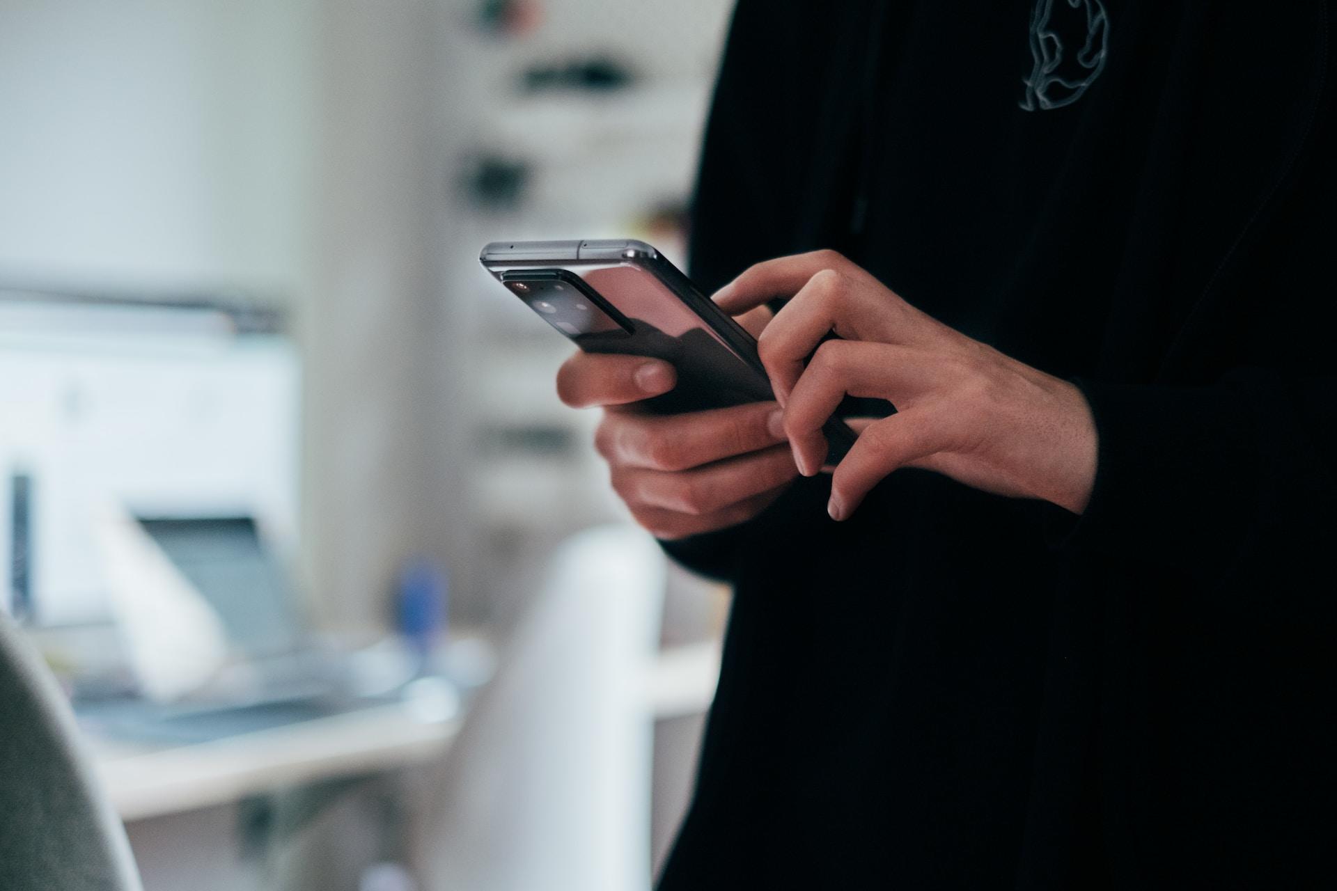 Woman holding a mobile phone in both hands.