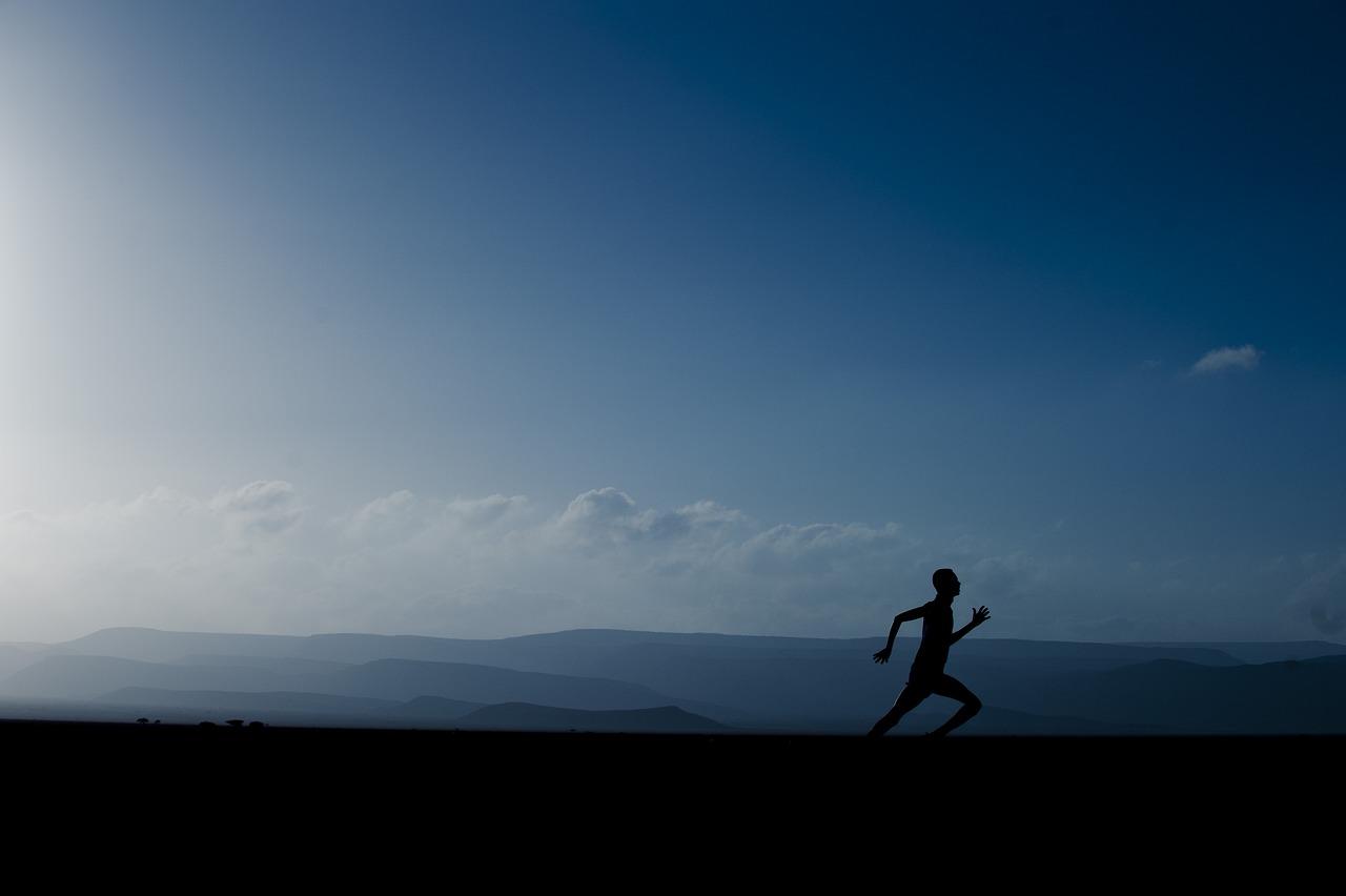 a man running in the mountains with a bright blue sky in the background