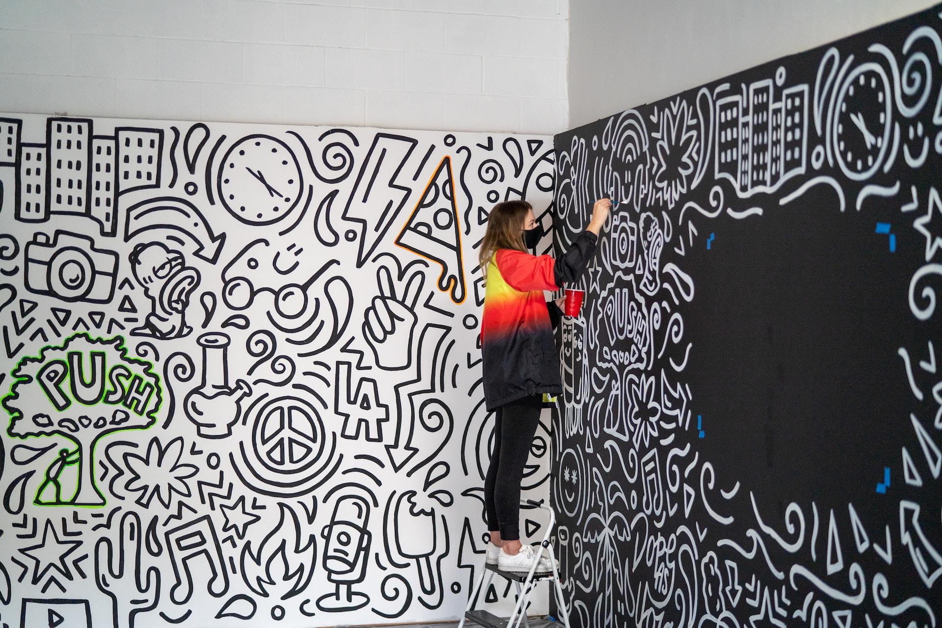 An artist creating a mural indoors.