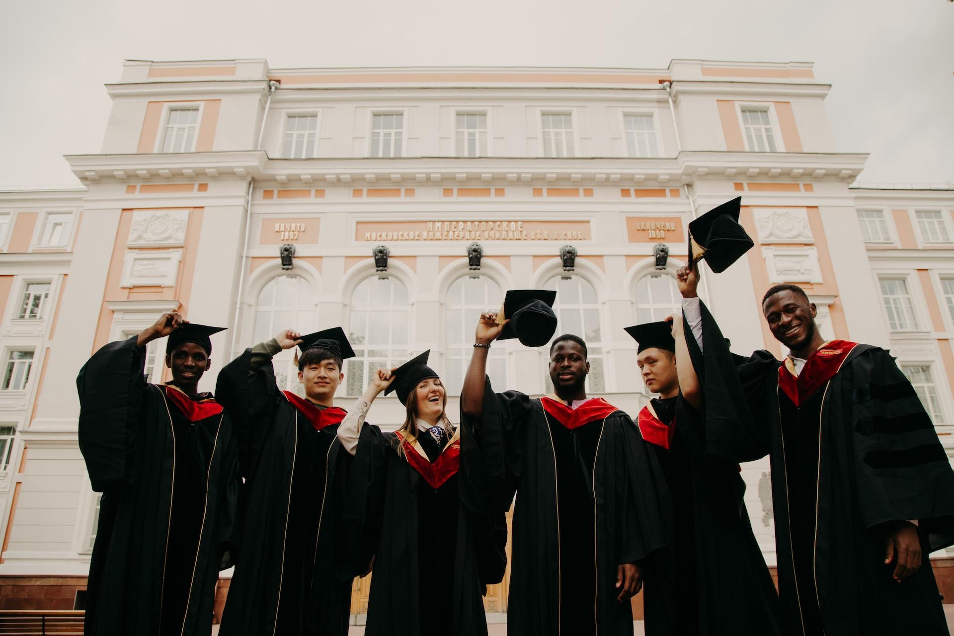 Six new graduates waving their hats in the air.