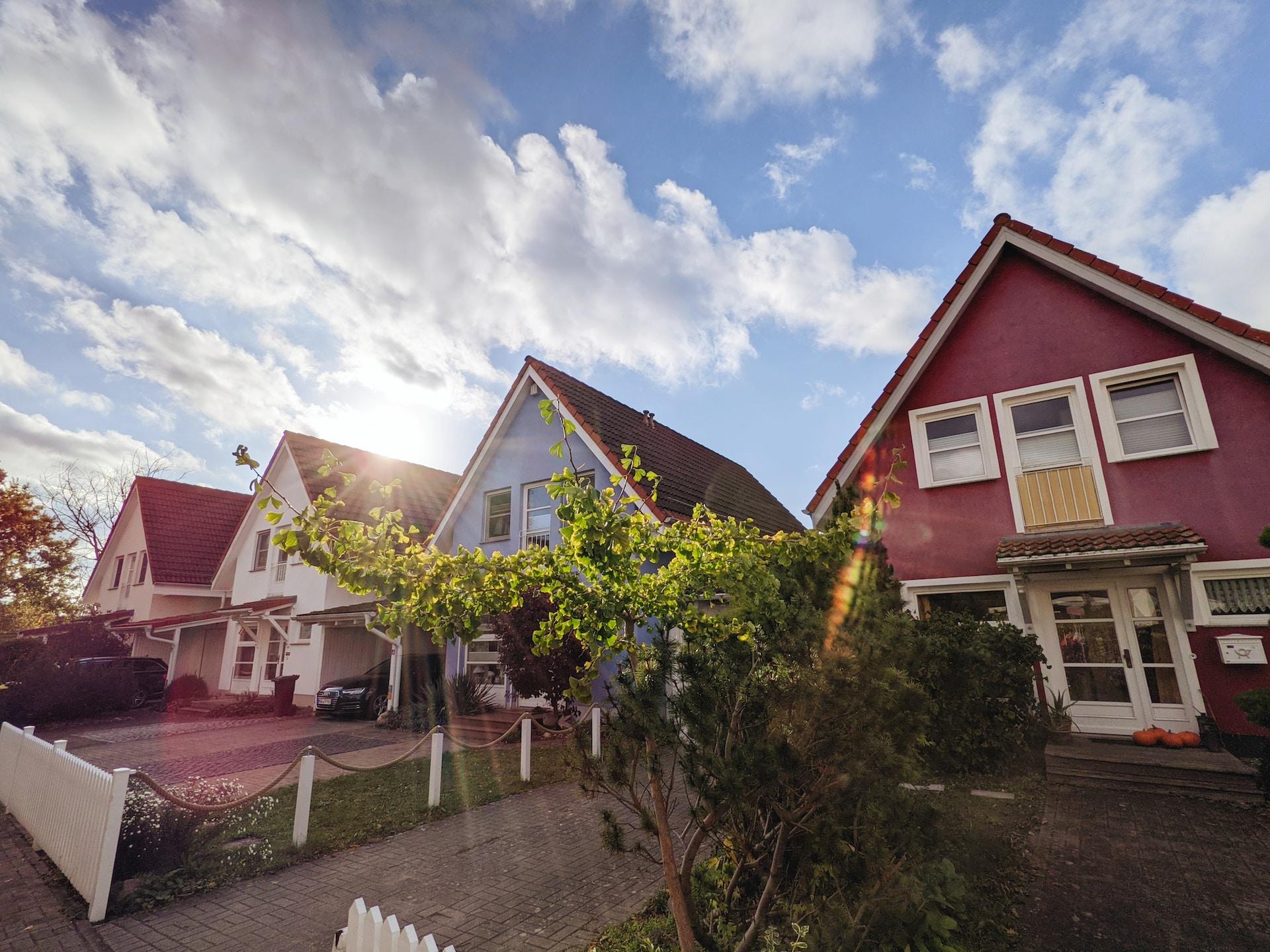 A row of two-storey houses, all the same design but painted different colours, mark their property lines with white picket fences and decorative chains.