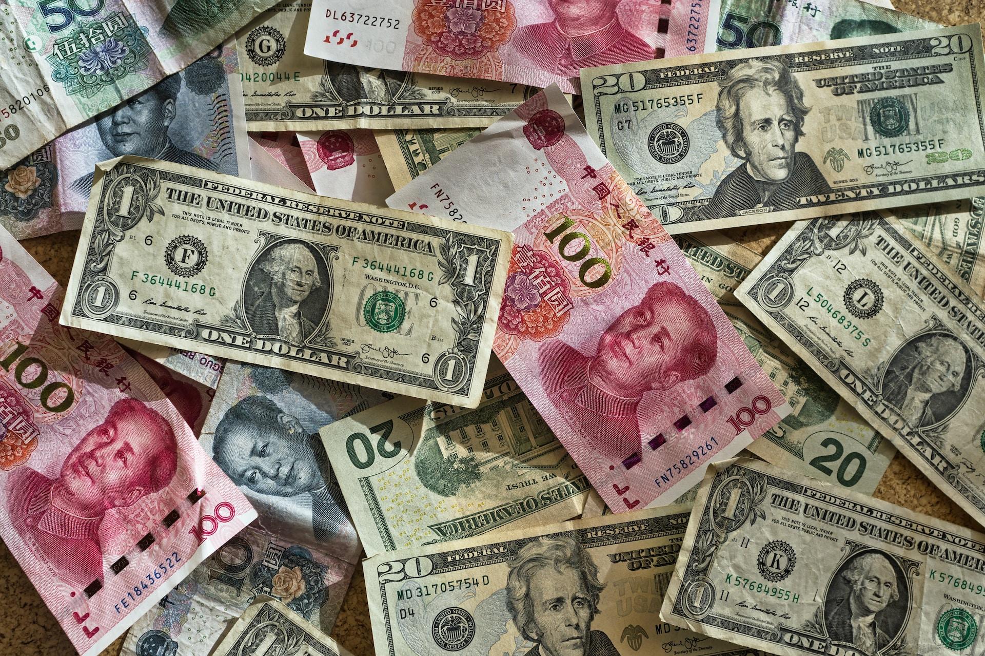 A scattering of various denominations of green and white dollars with a few pink 100 yuan notes mixed in. 