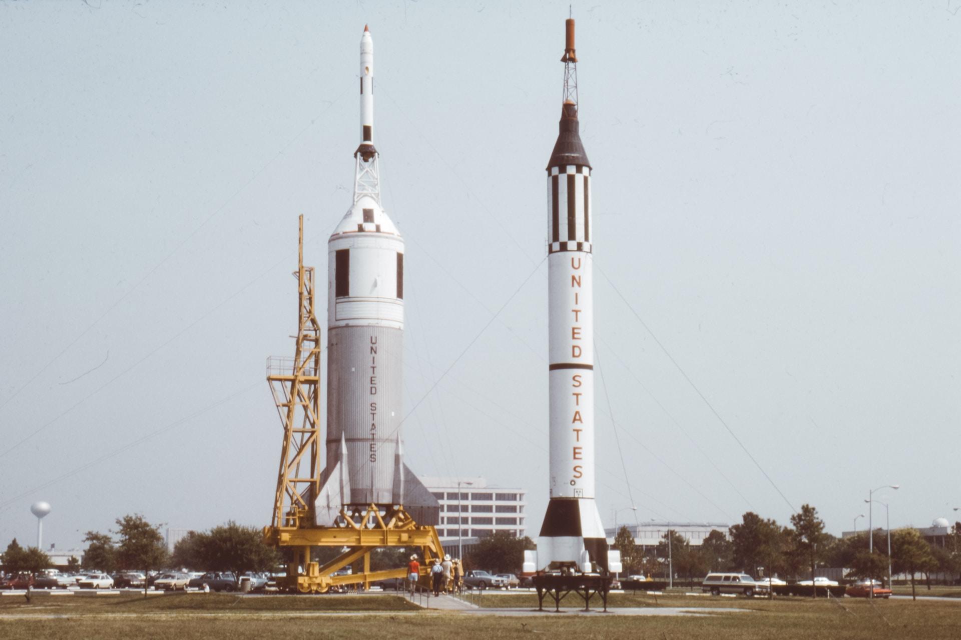 Two American rocket ships planted vertically, carve out the grey sky in the background.  