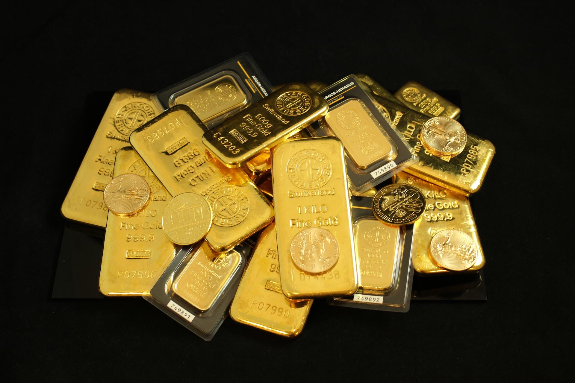 Gold bars and bullion in various weights scattered across a black background.