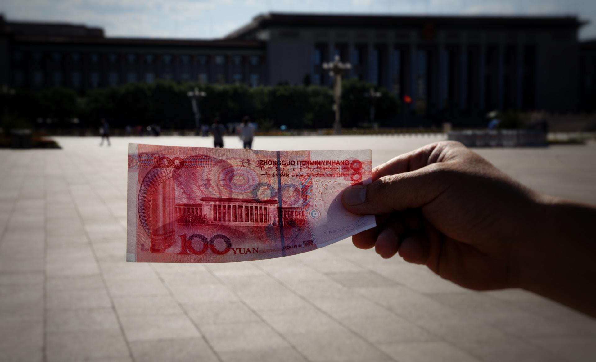 The early morning sun shines through a 100-yuan bill with the expanse of Tiananmen Square and the People's Parliament in the background.