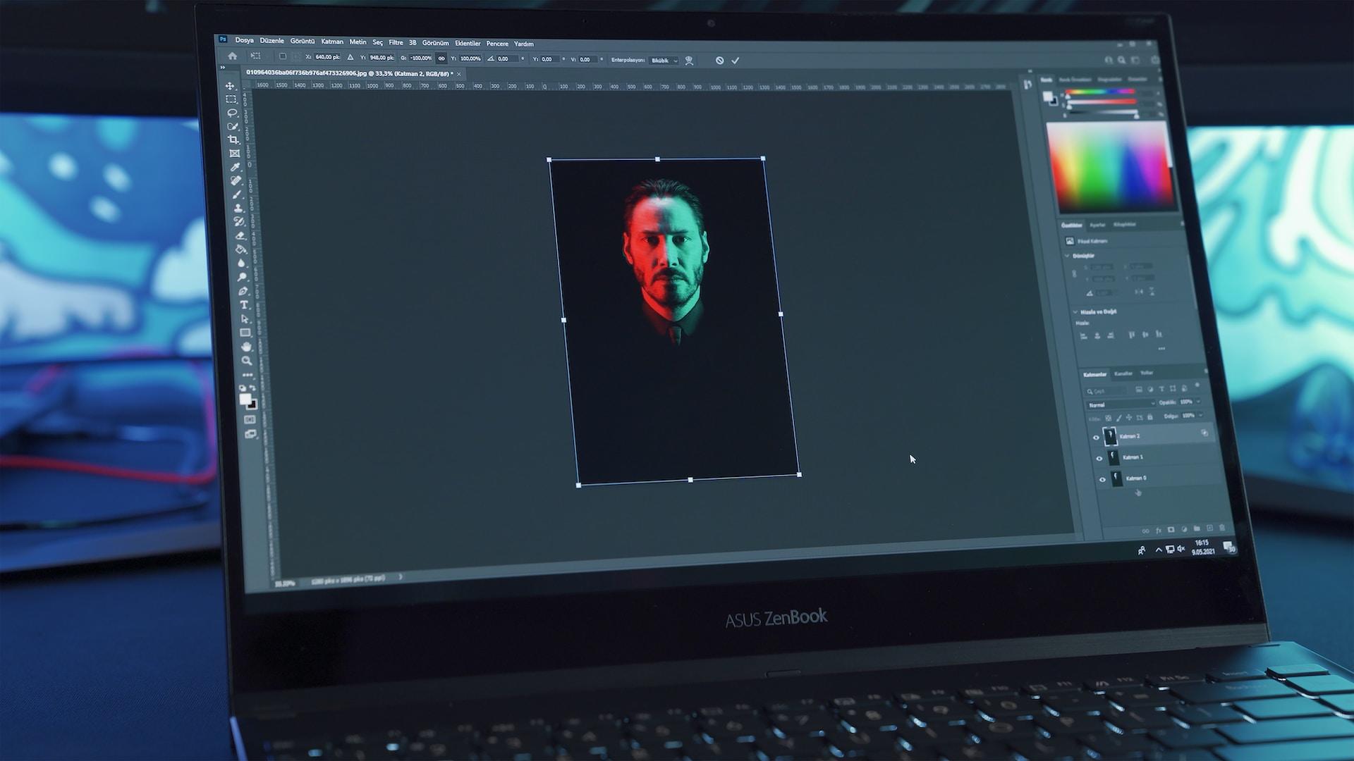 An open laptop computer displaying an open software application set to edit Keanu Reeves' face, which is lit with a red light on one side and a greenish light on the other.