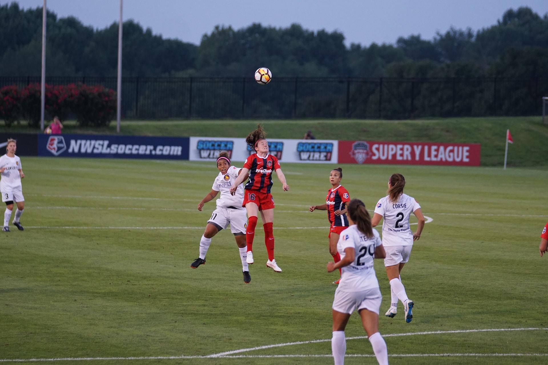 A female soccer player heading the ball during a match.