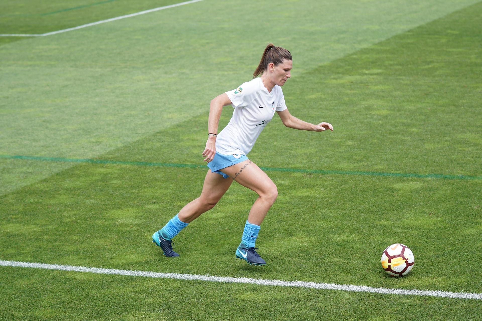 A female soccer player running with the ball.