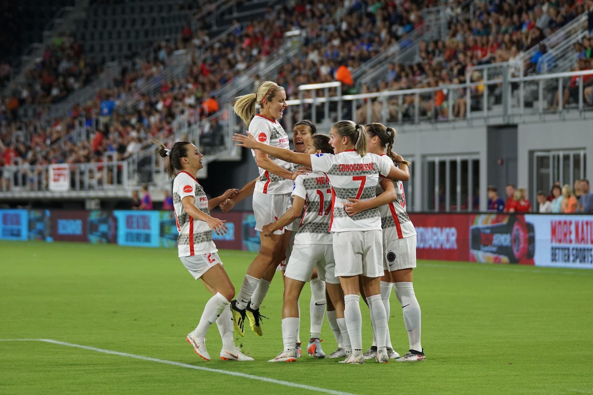 A women's soccer team celebrating a goal.