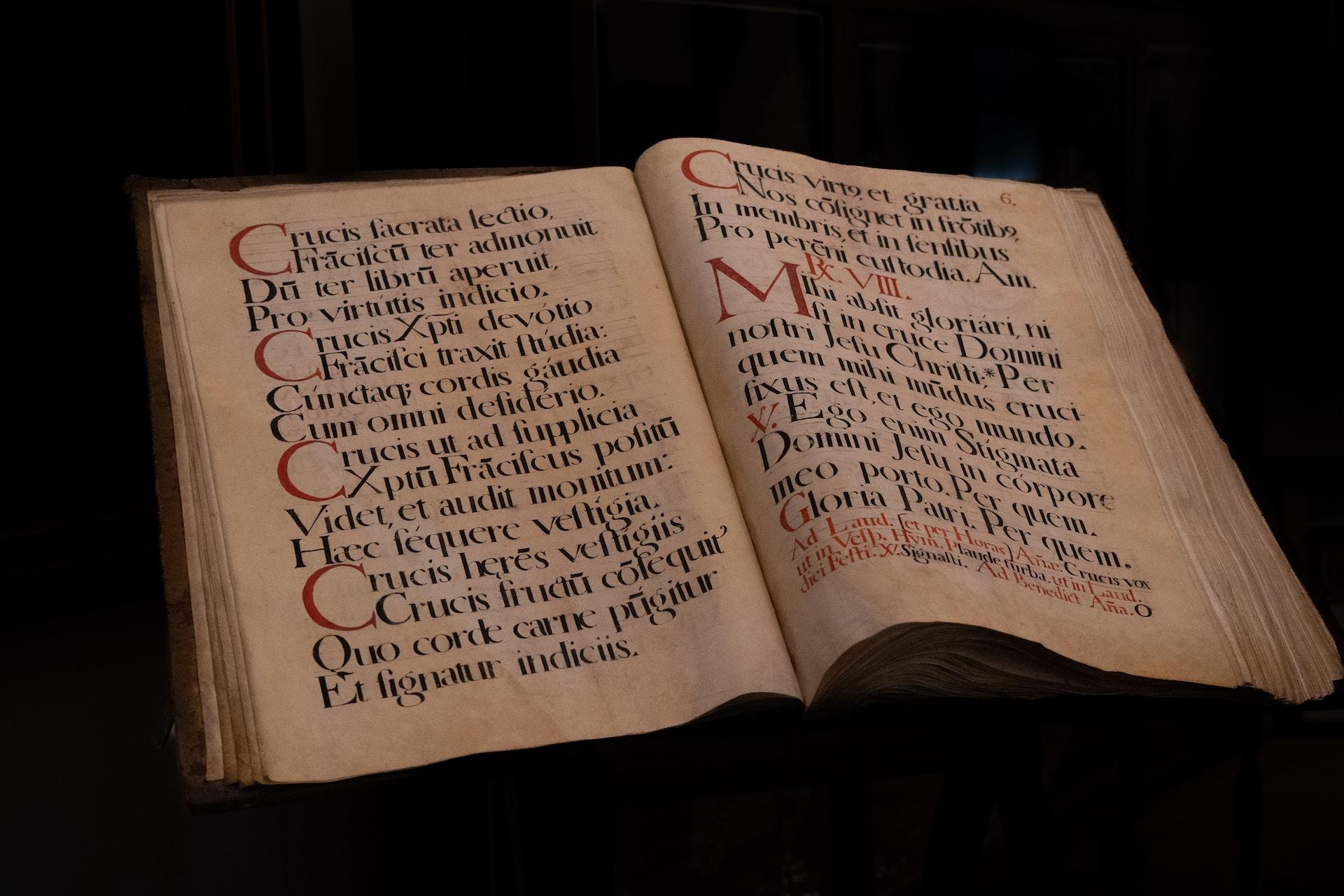 An old handwritten Bible in Latin lies open on a table.