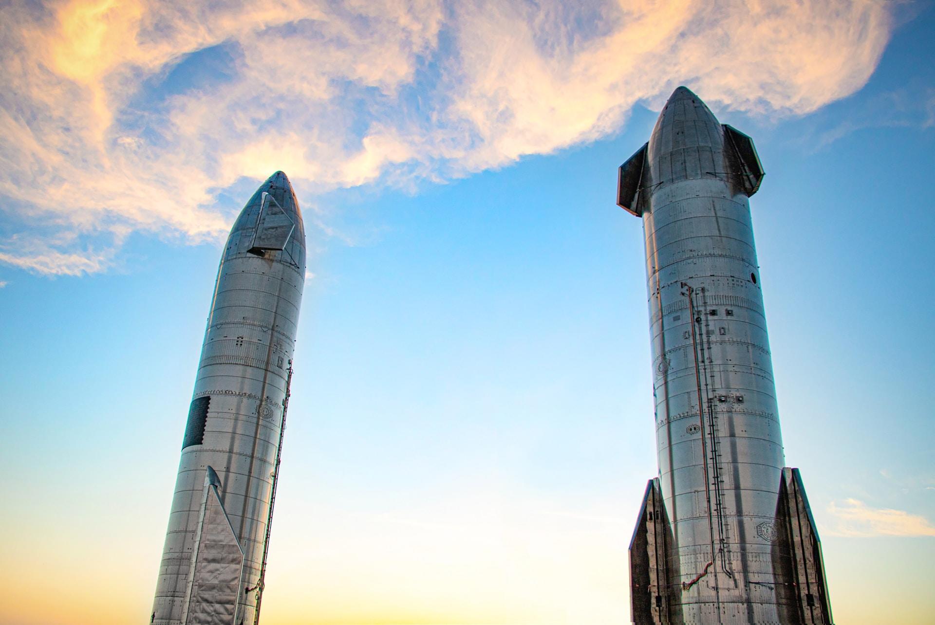 Twin grey rockets in vertical launch position against a blue sky at dawn.  