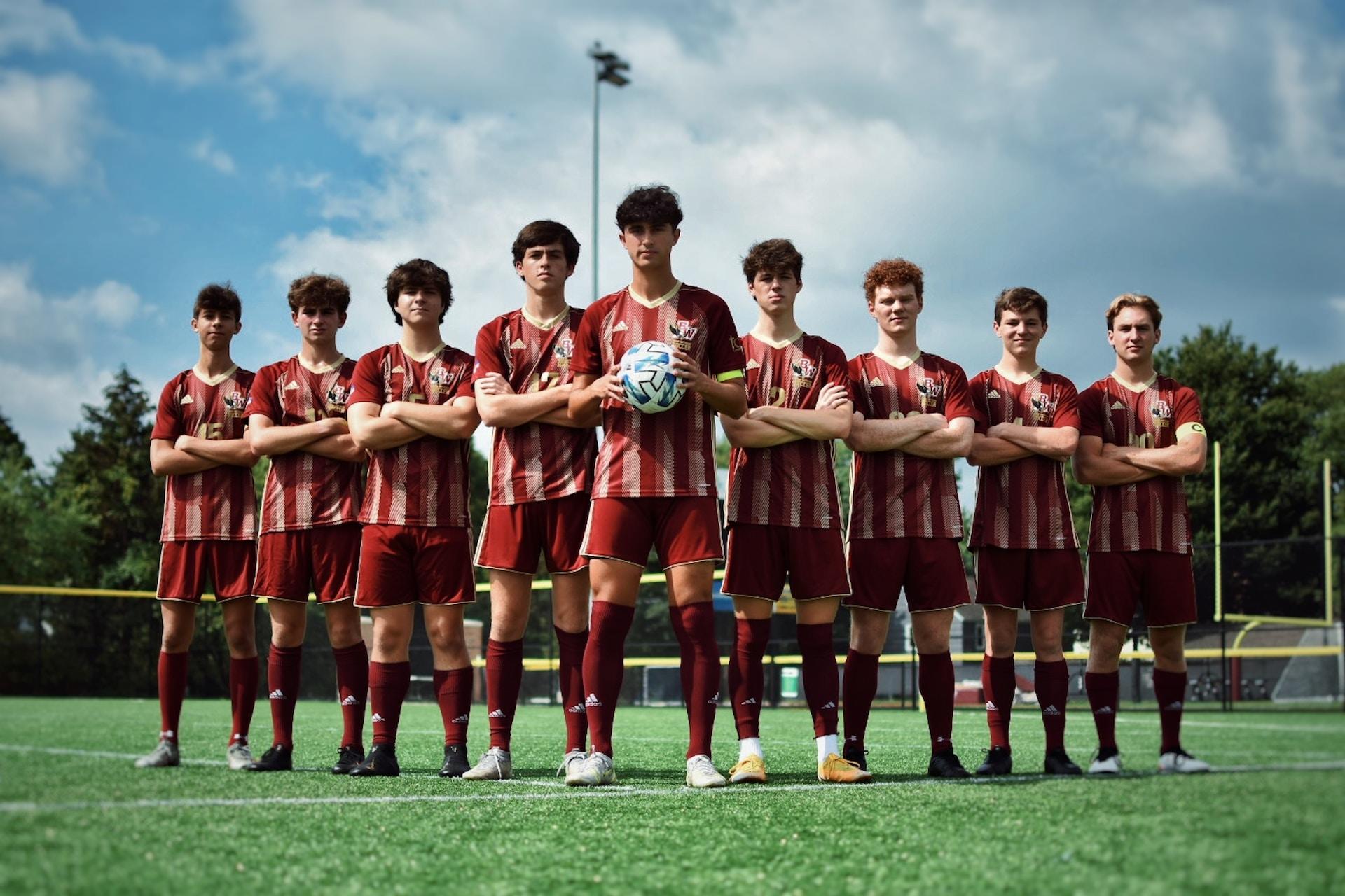 A team of soccer players dressed in their red and white uniform, stands arranged on a football pitch.