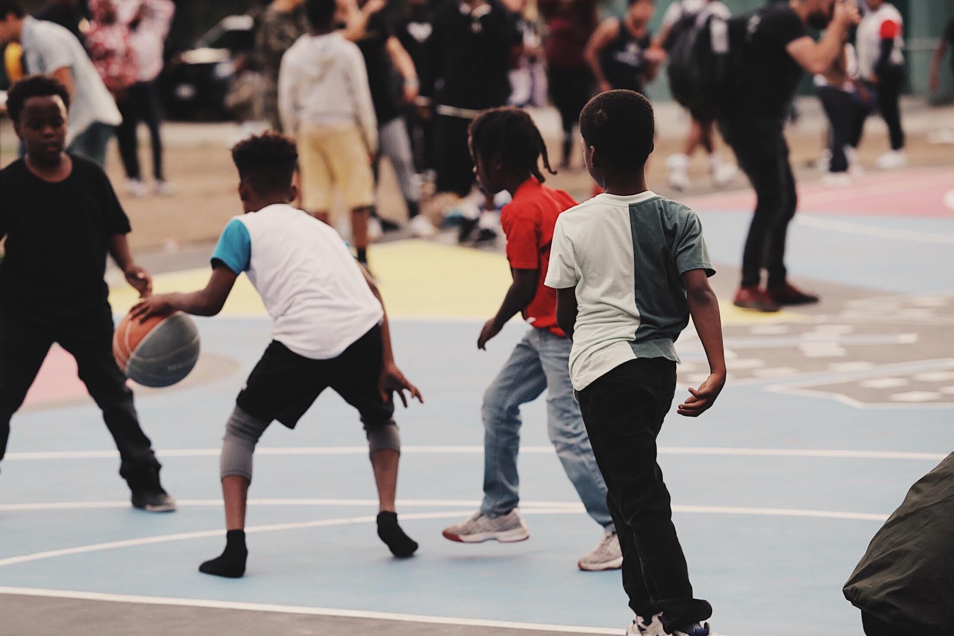 Children playing basketball on an outdoor court.