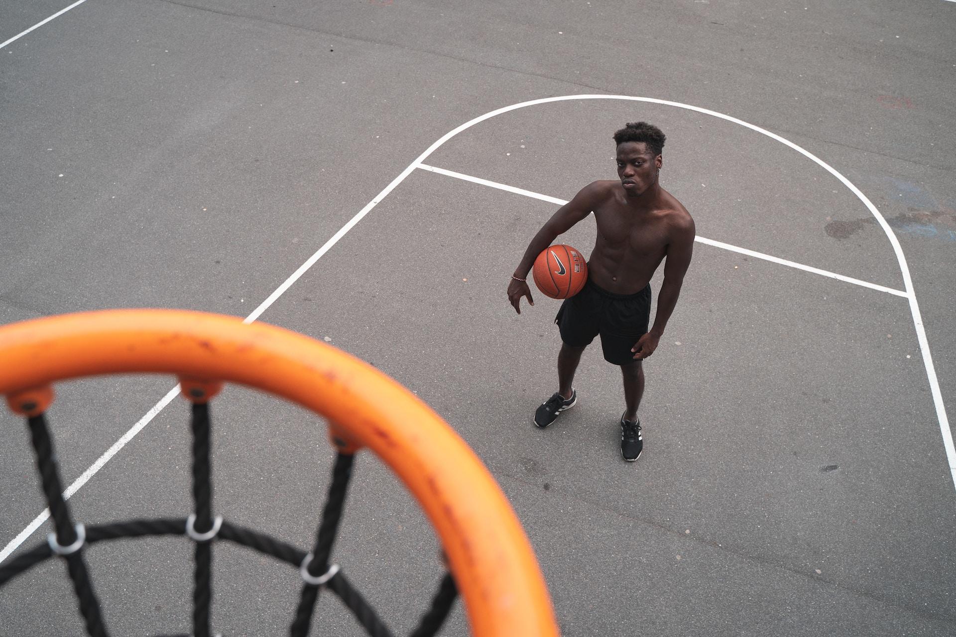 A man with a basketball looking at the basketball net.