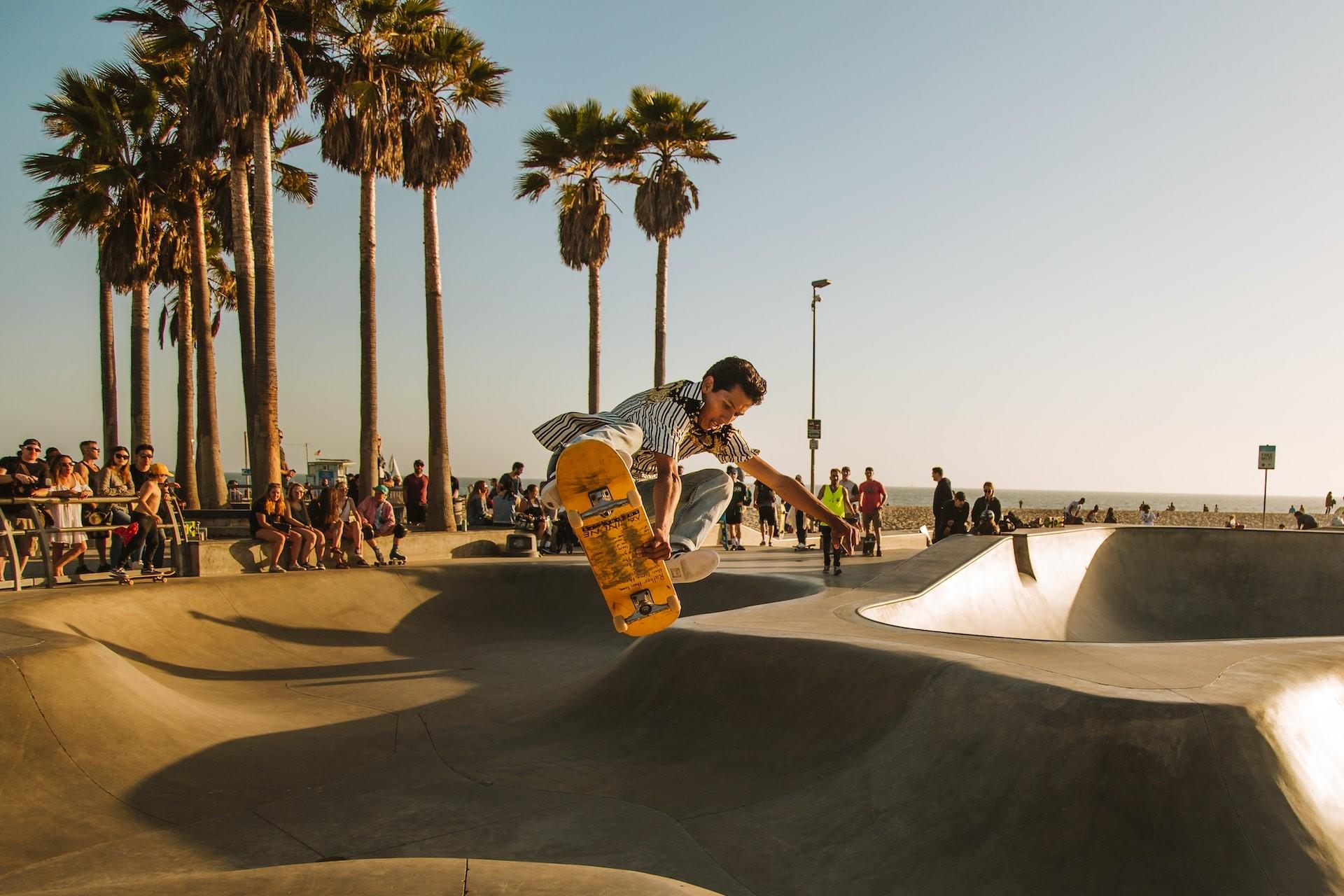 A skateboarder getting air out of a bowl in a skatepark.
