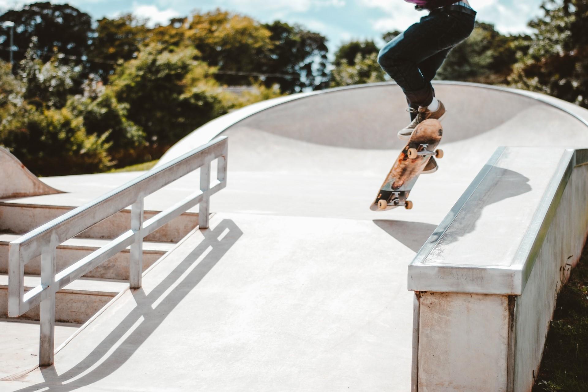 A skateboarder doing a trick on a ramp by a rail.