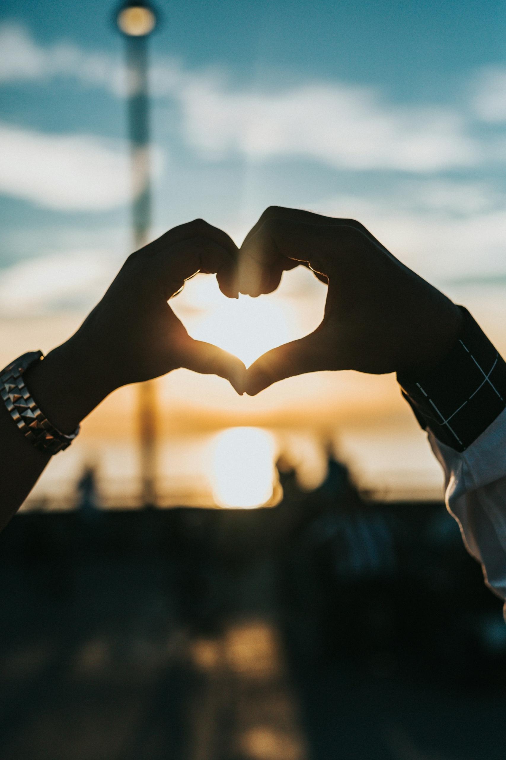 People holding hands together in heart form in an evening scene
