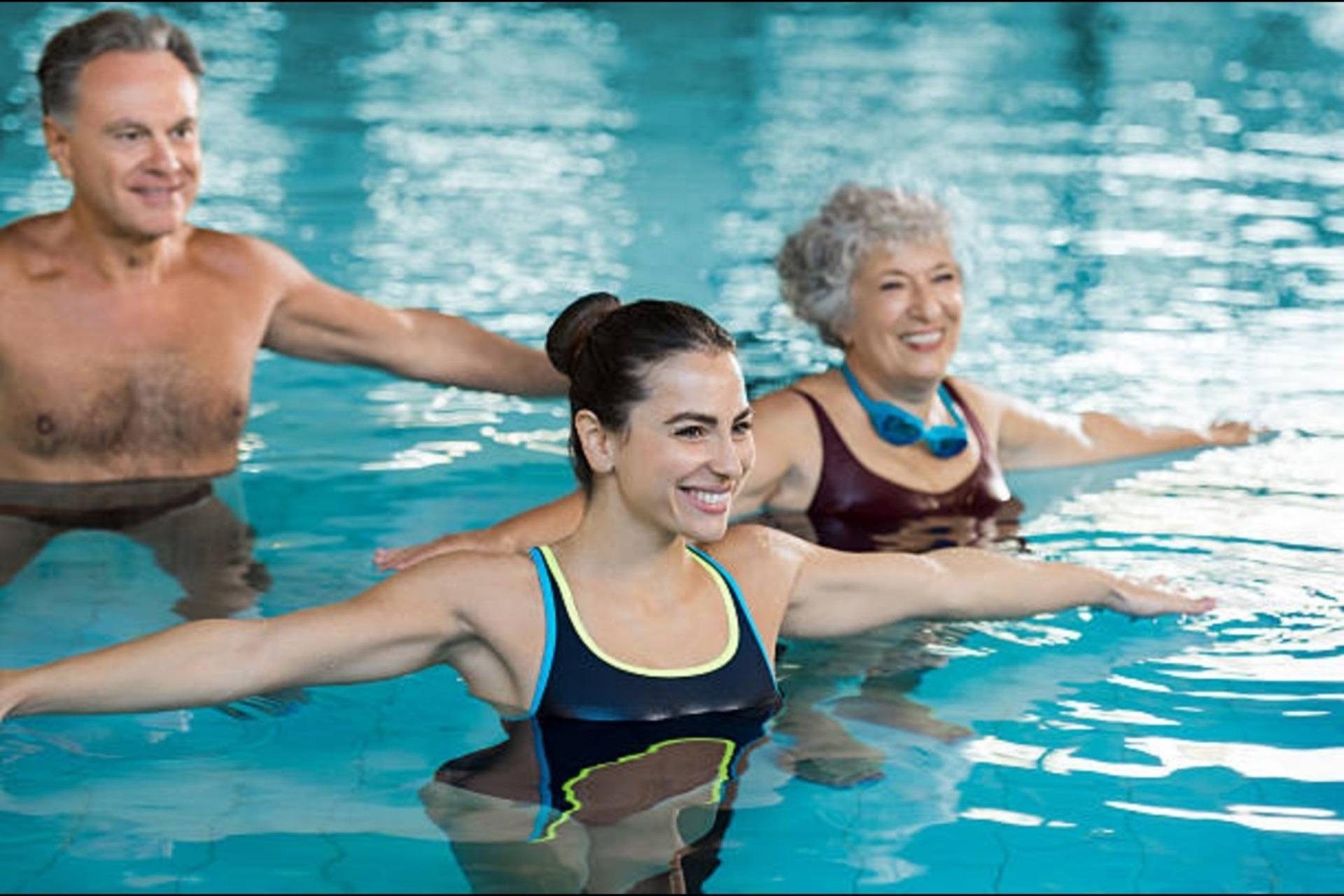 Different-aged people doing aerobics in a swimming pool.