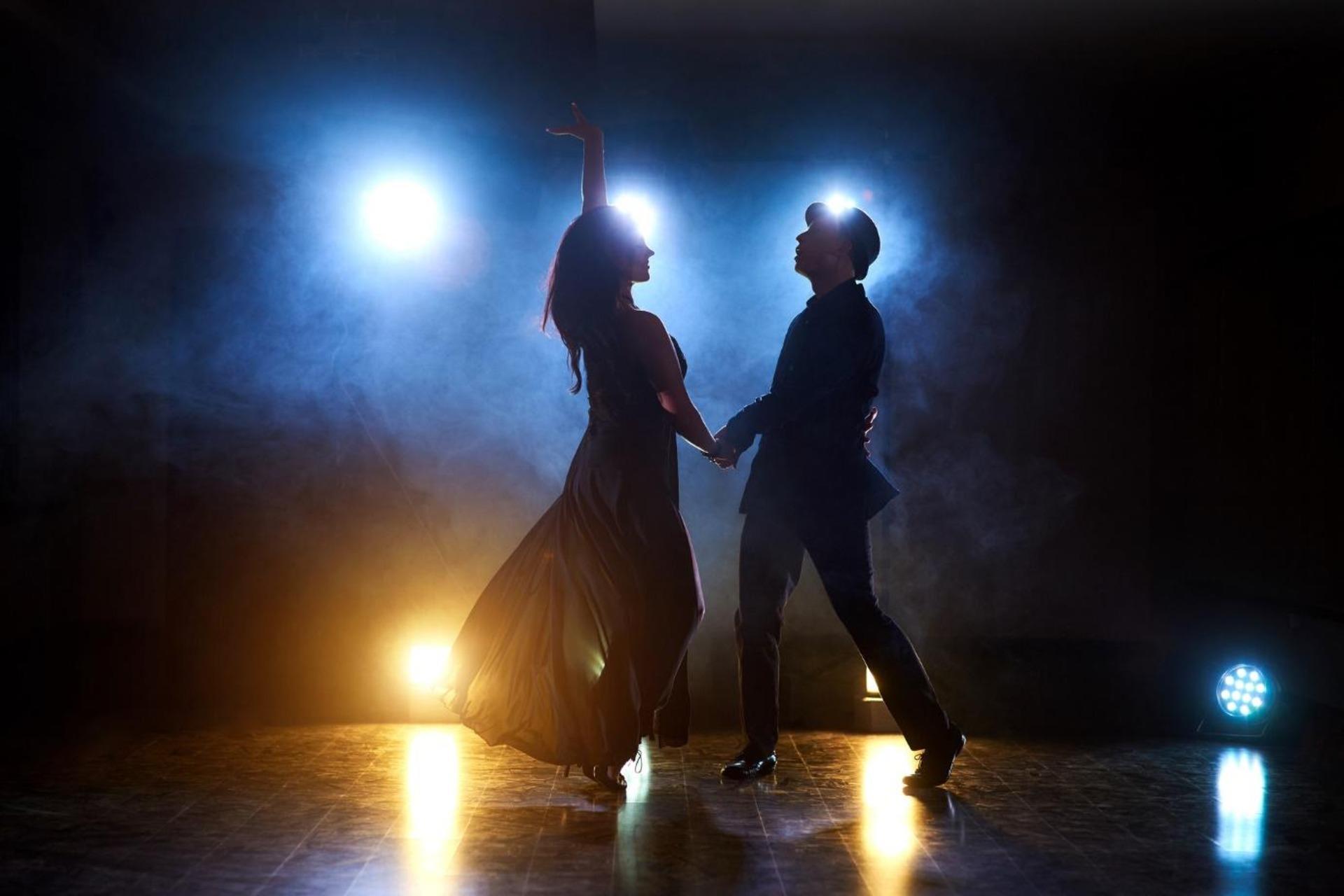 Skillful dancers performing in theatre under the spotlight.