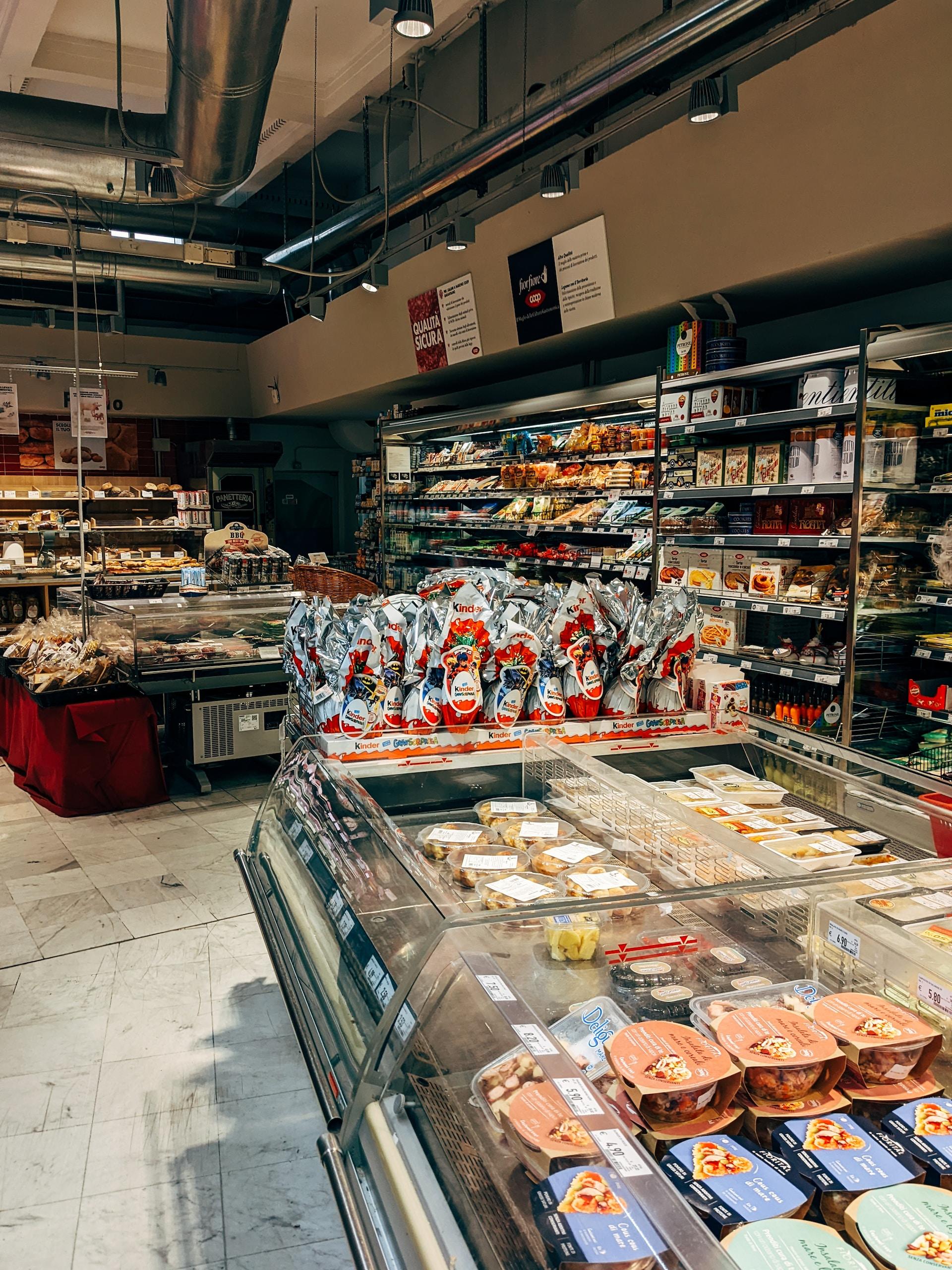 A supermarket section with diffused lighting featuring refrigerated cases with wares attractively laid out, but no shoppers.  