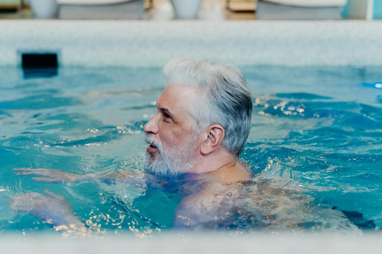 An older man swimming in a pool.