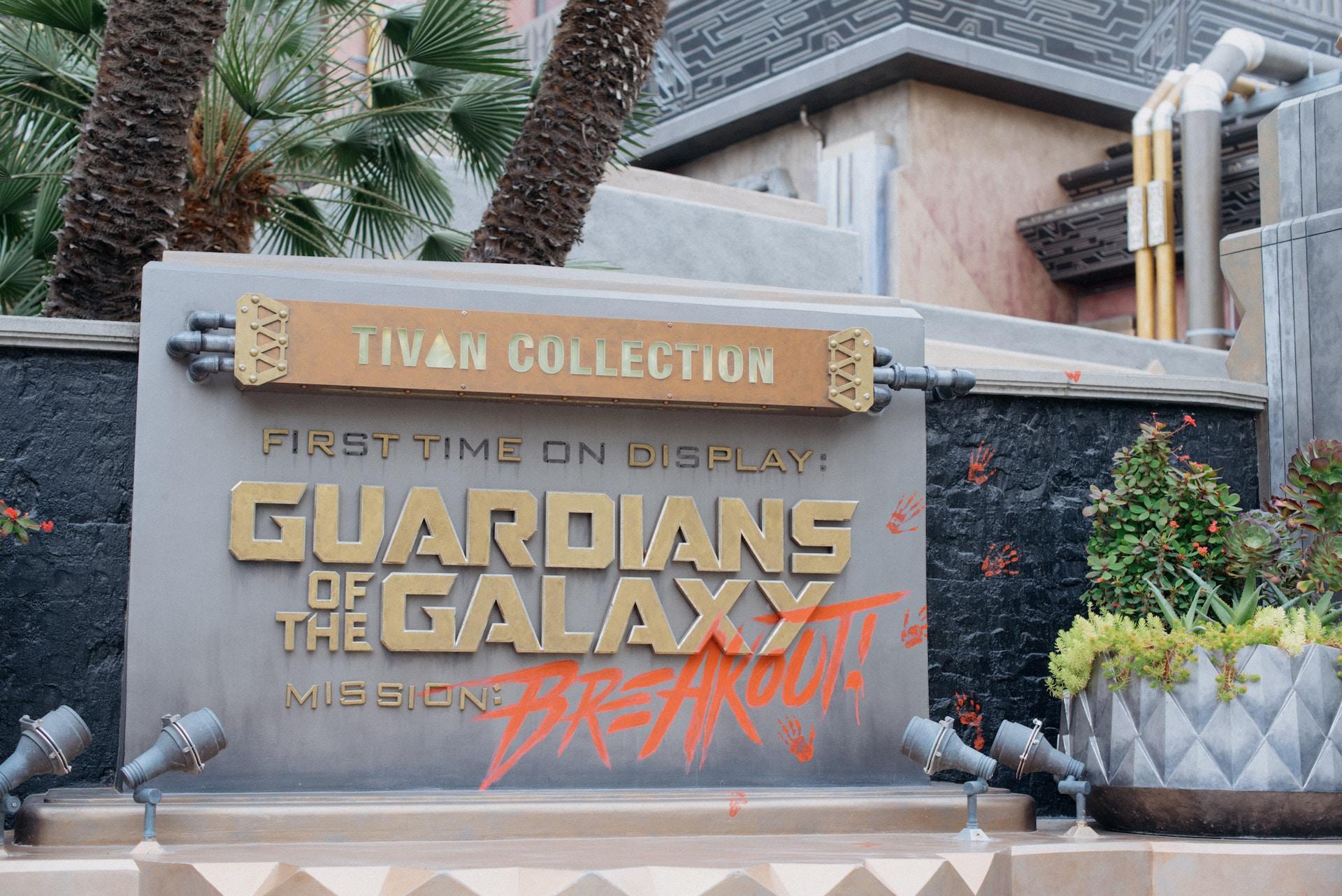A grey and gold museum sign advertising a Guardians of the Galaxy exhibit, with the word 'breakout' seemingly sprayed on in bright orange paint. 