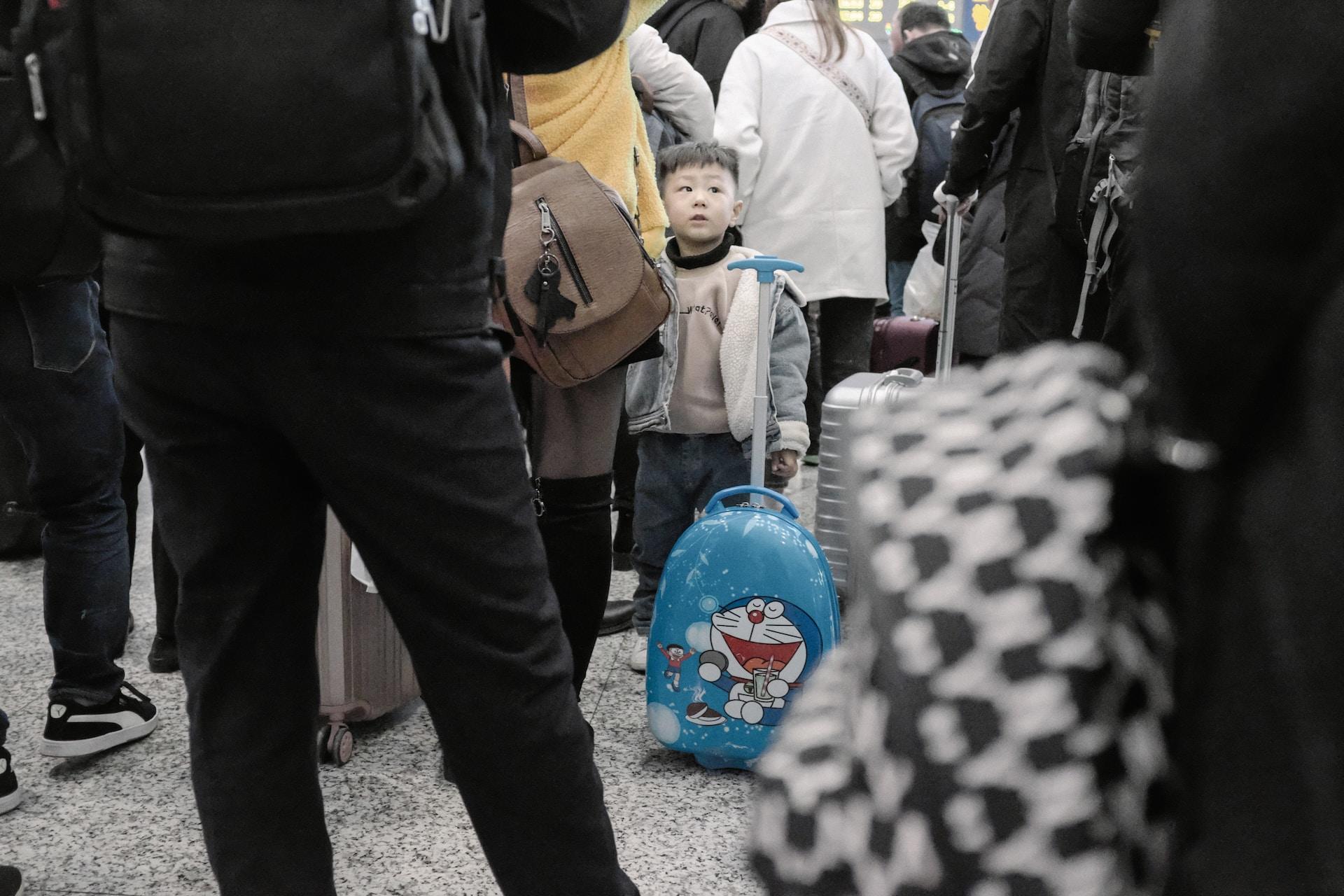A kid with his mom waiting in line in a train station.