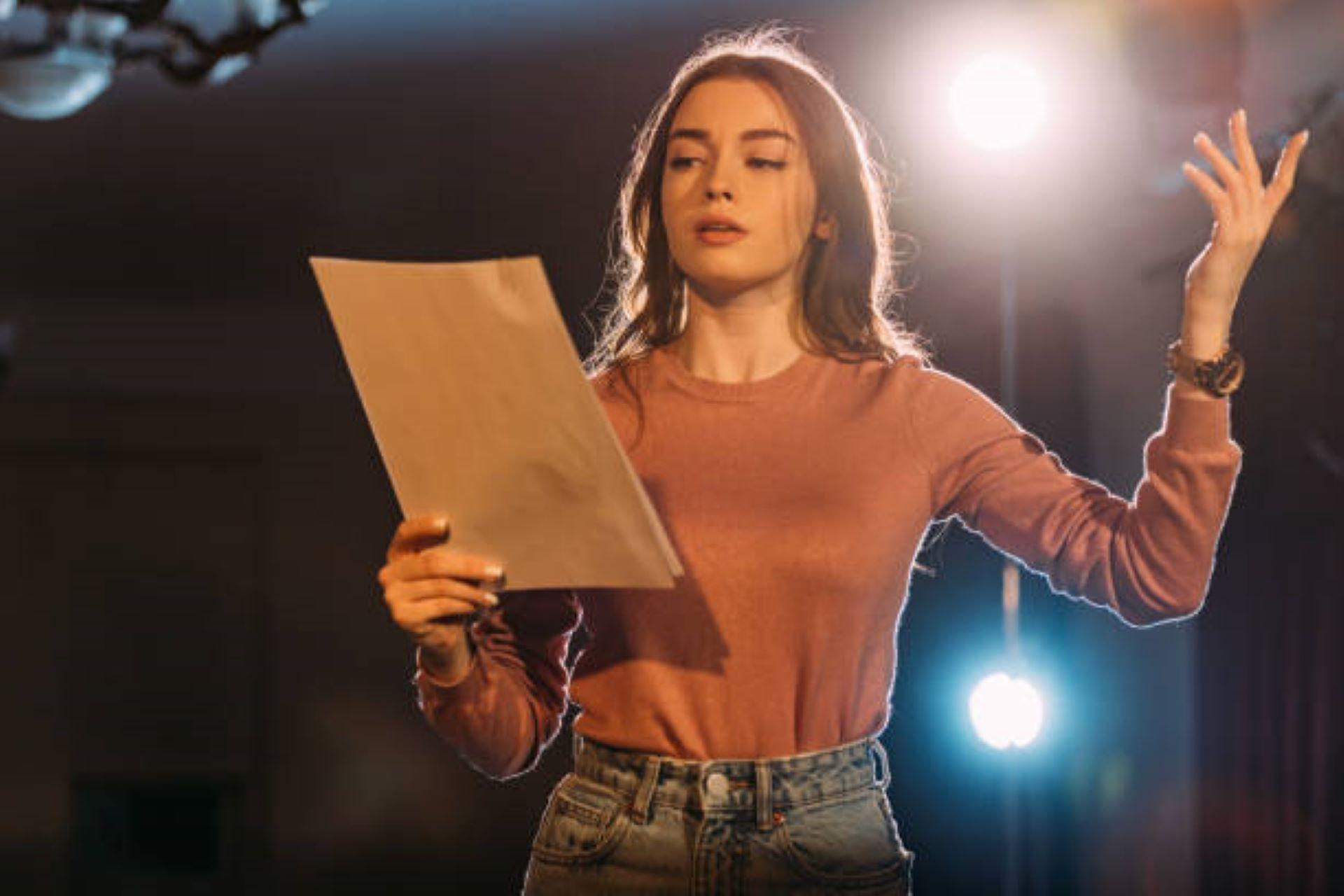Young actress reading a scene on stage in a theatre.
