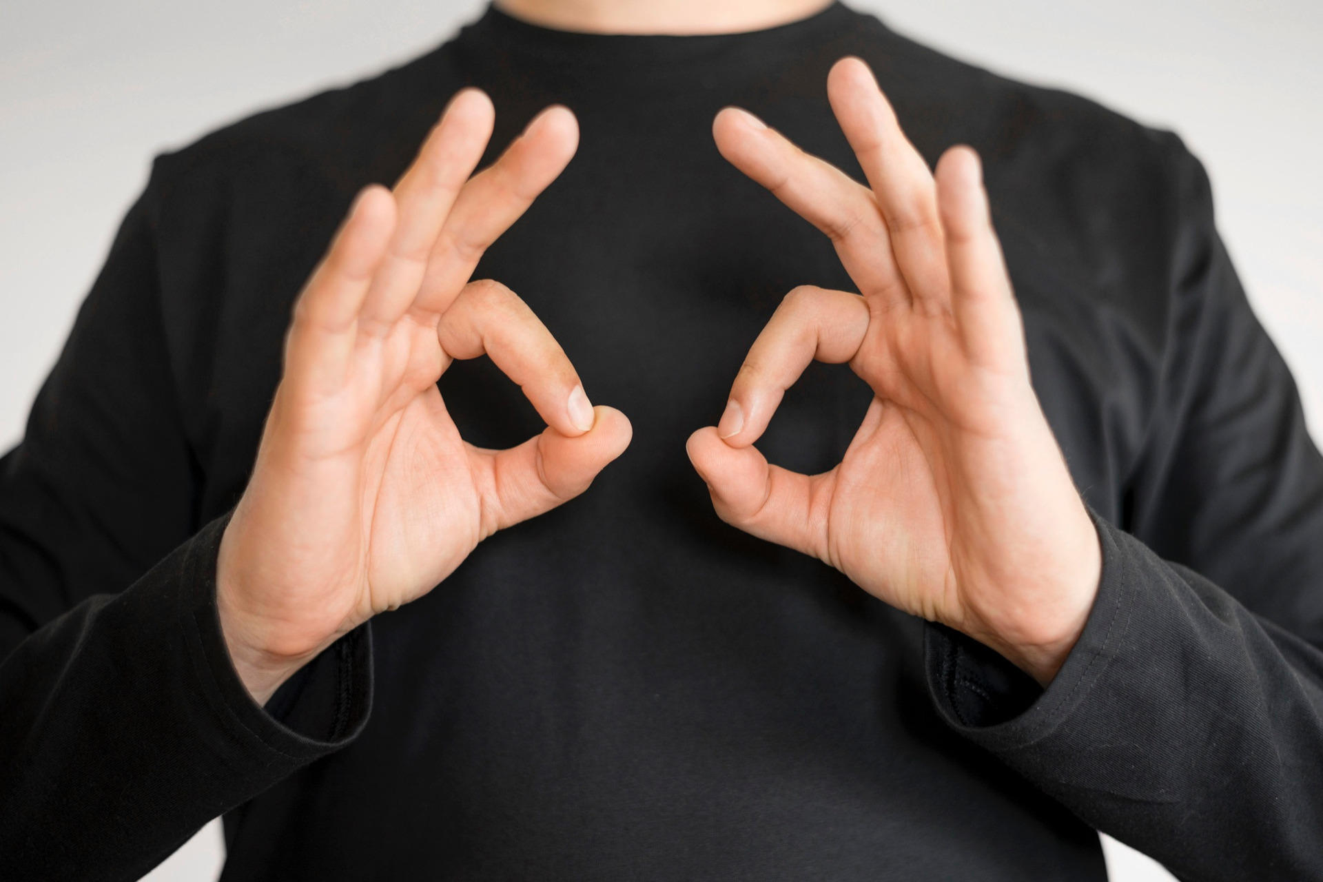 A man in a black shirt using sign language.