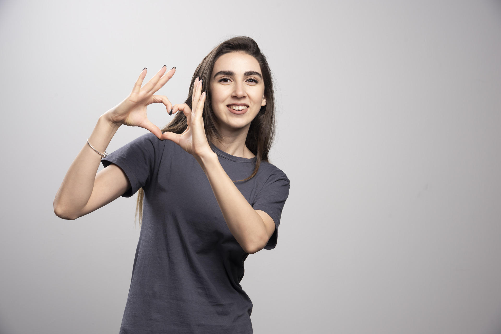 Cheerful girl clasping hands in a sign language gesture.