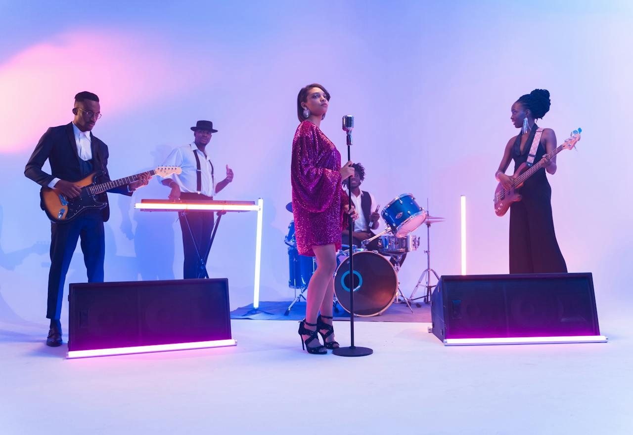 A 5 piece band in a white backdrop with neon lights posing for photos