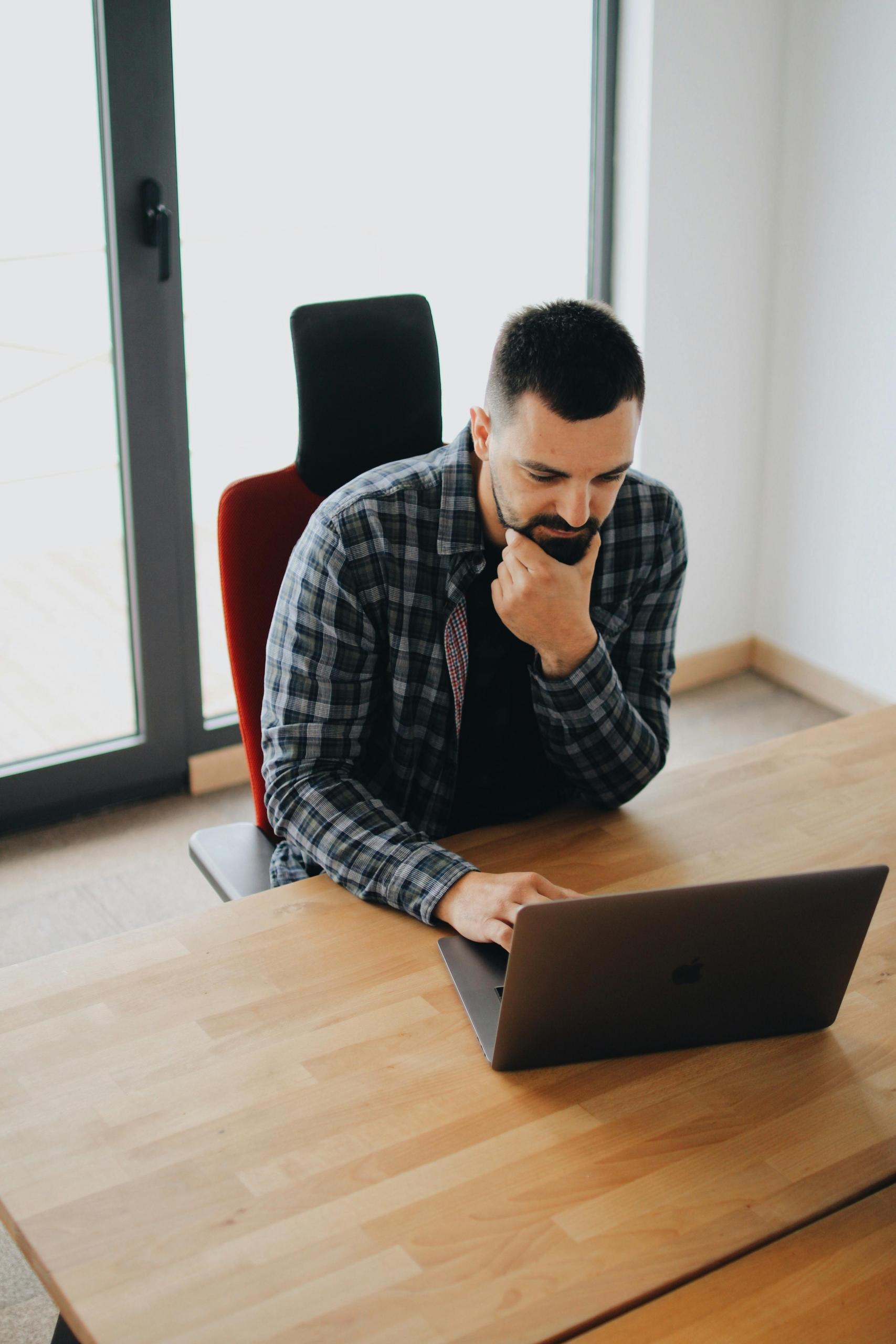 A data analyst sitting working at his desk with a laptop.