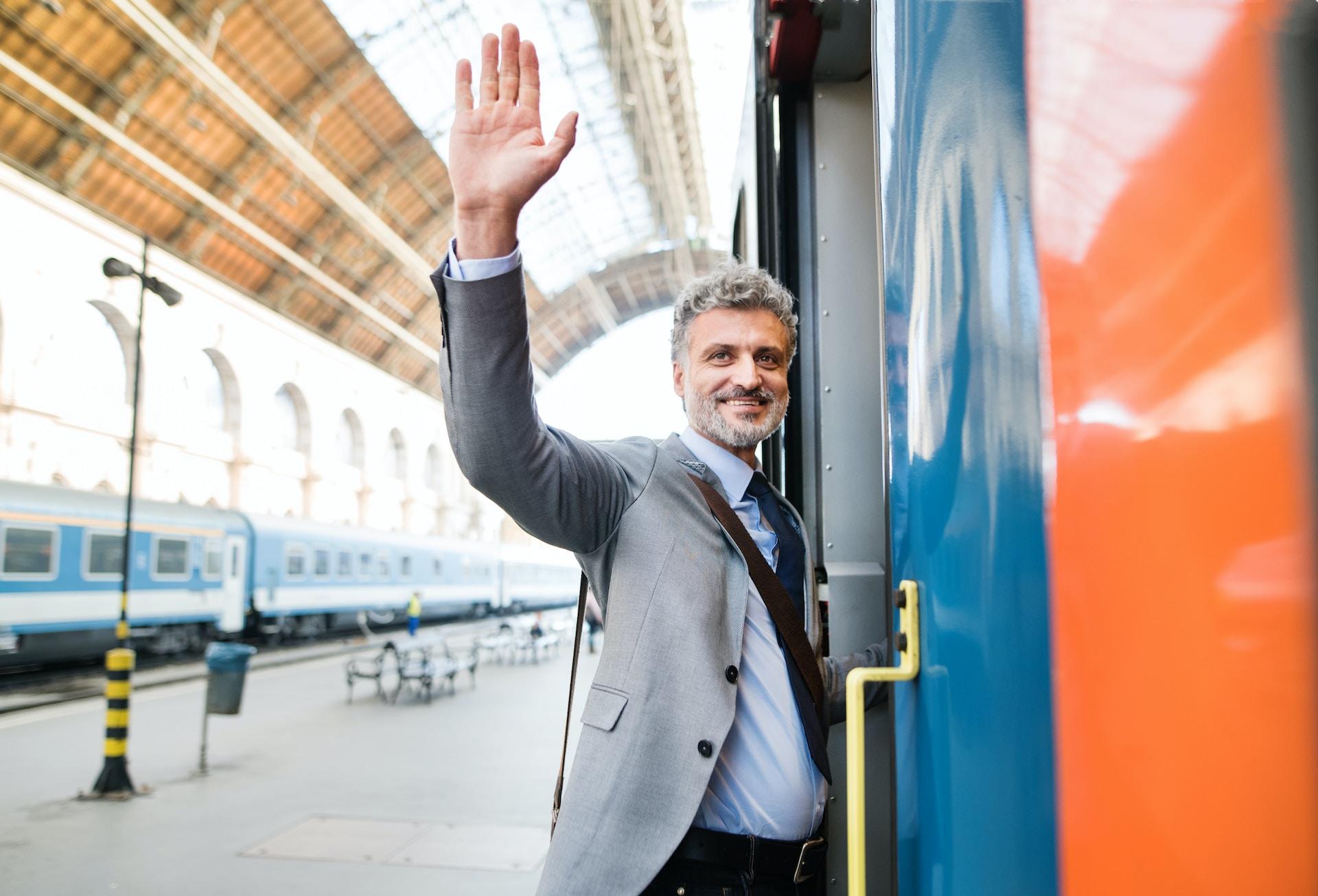 Man waving goodbye while getting on a train.